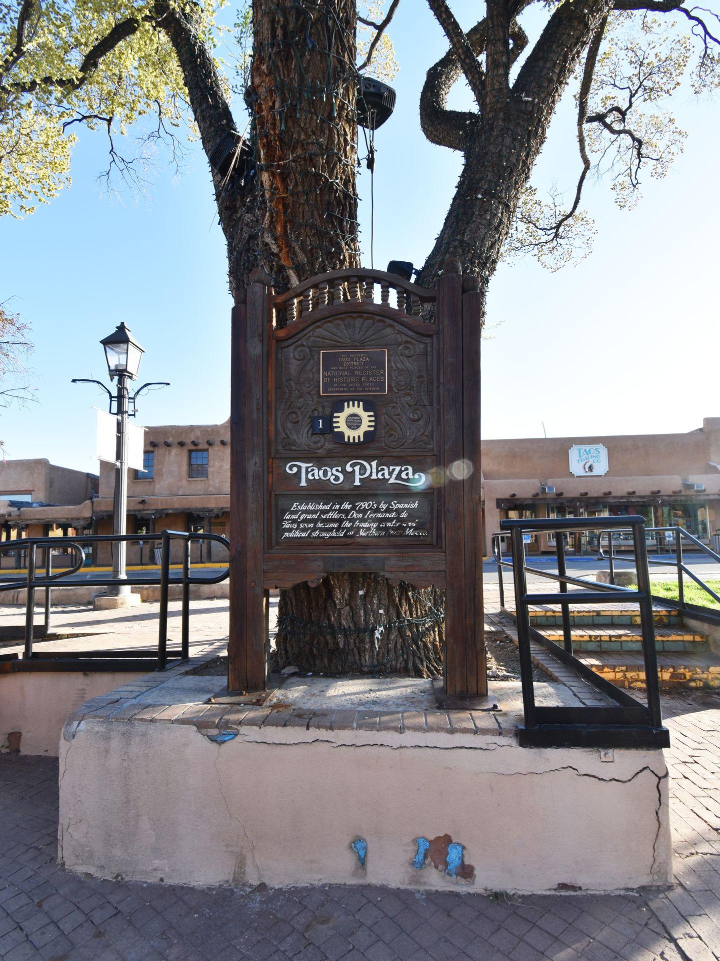 A large brown sign that says "Taos Plaza" with a brief history of the area.