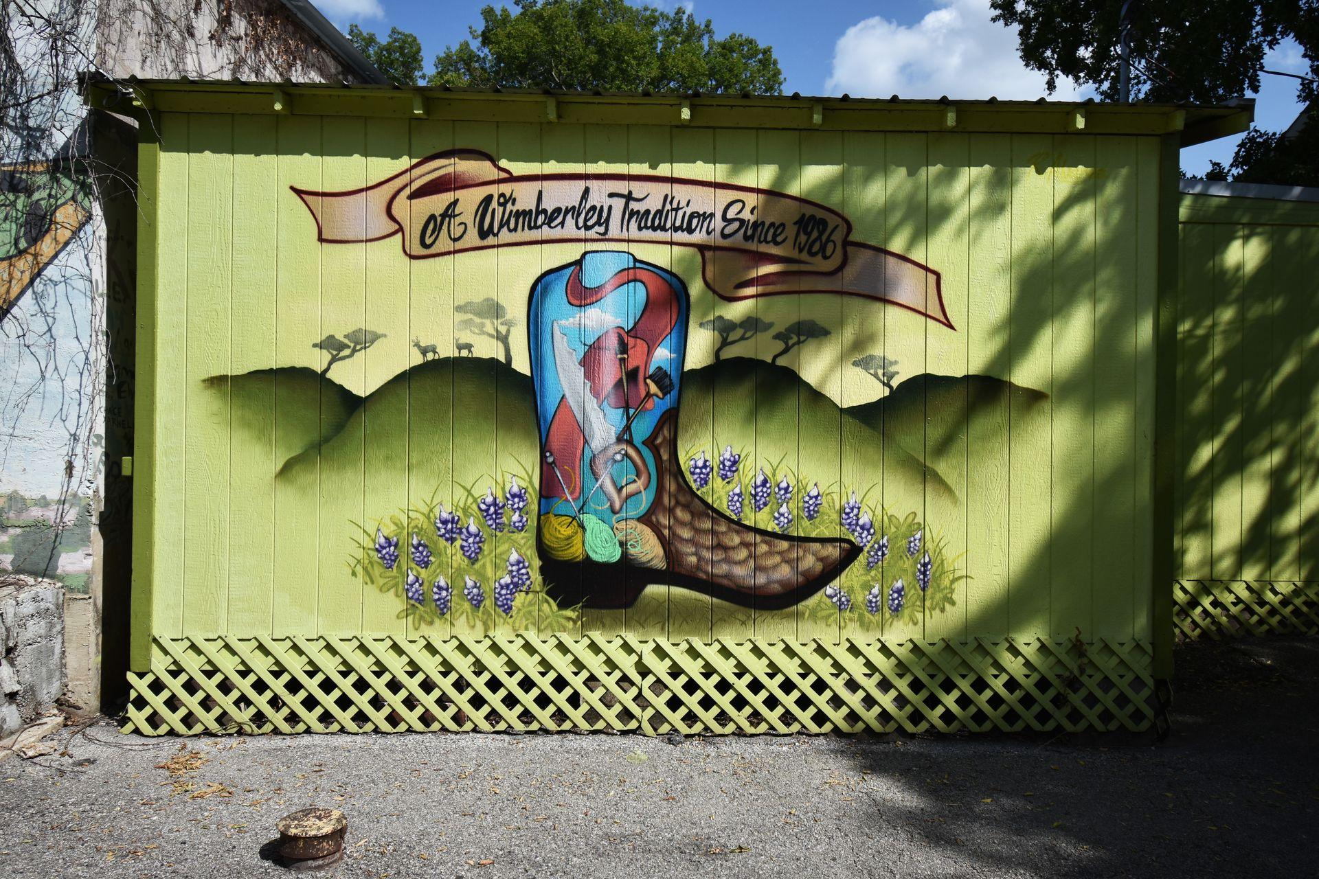 A mural with a painted cowboy boot that reads "A Wimberley Tradition Since 1986"