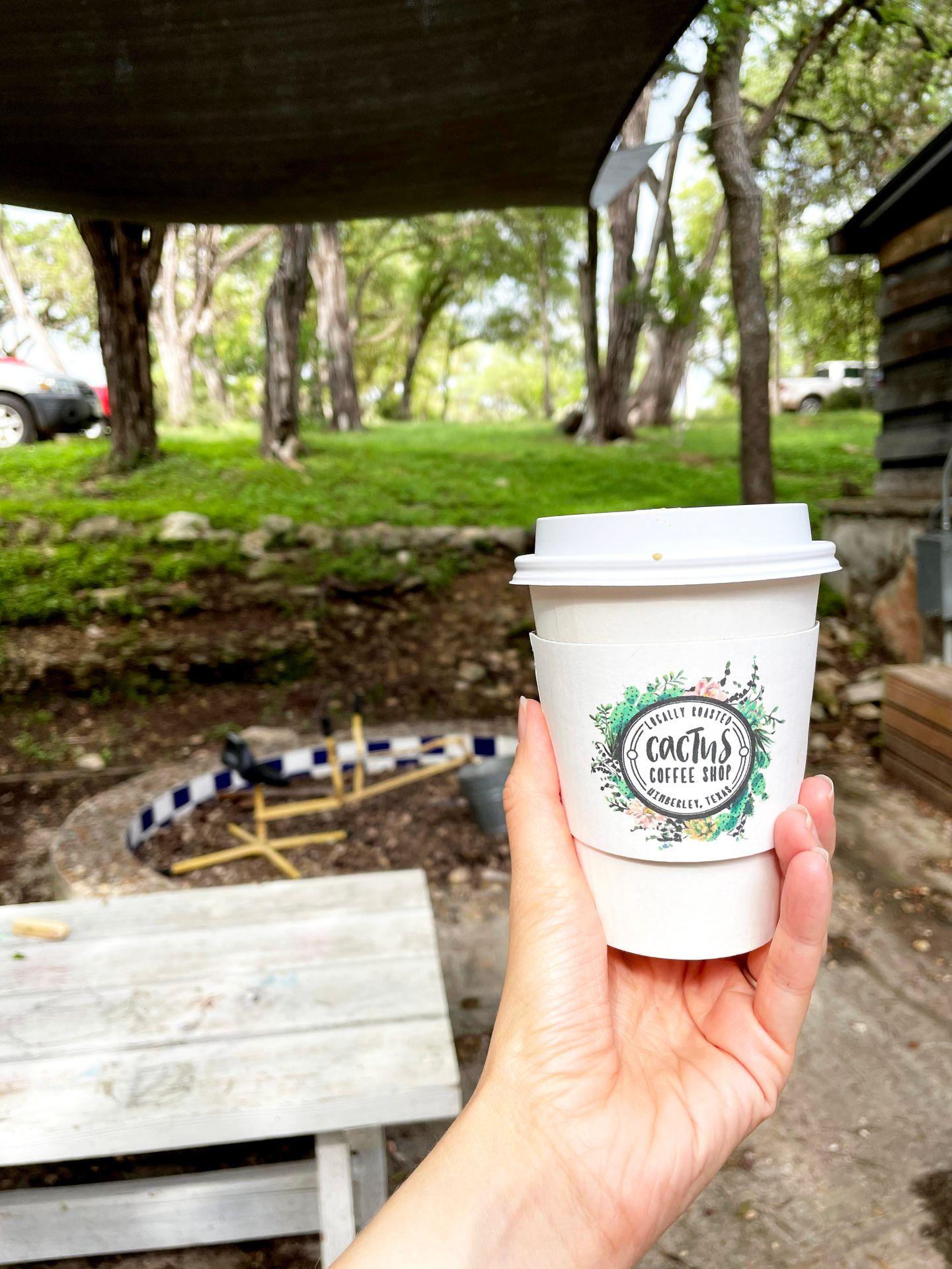 Holding up a coffee cup outside of Sugar Shack Bakery.