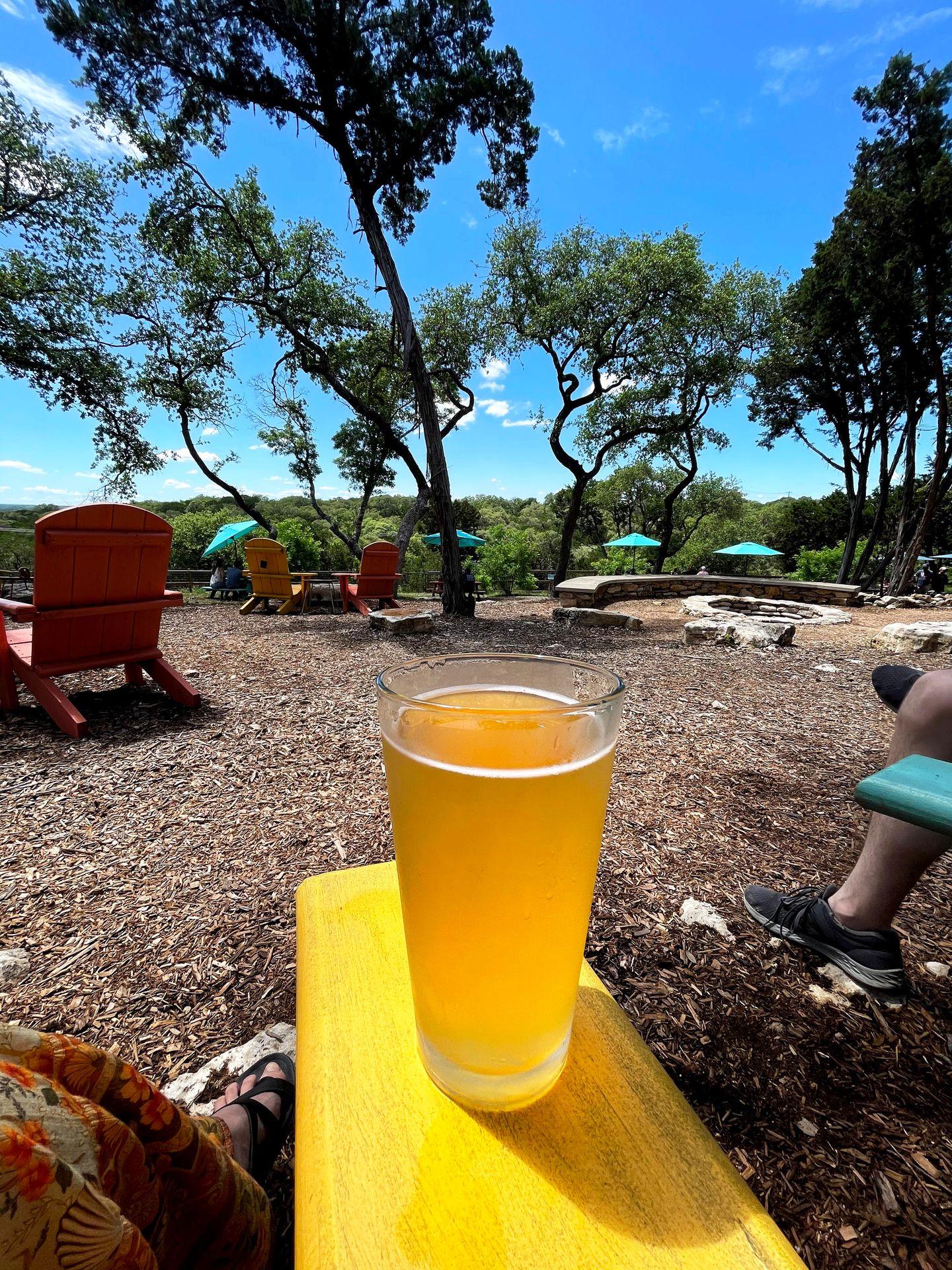 A glass of light-colored beer sitting on a yellow lawn chair at Shady Llama.