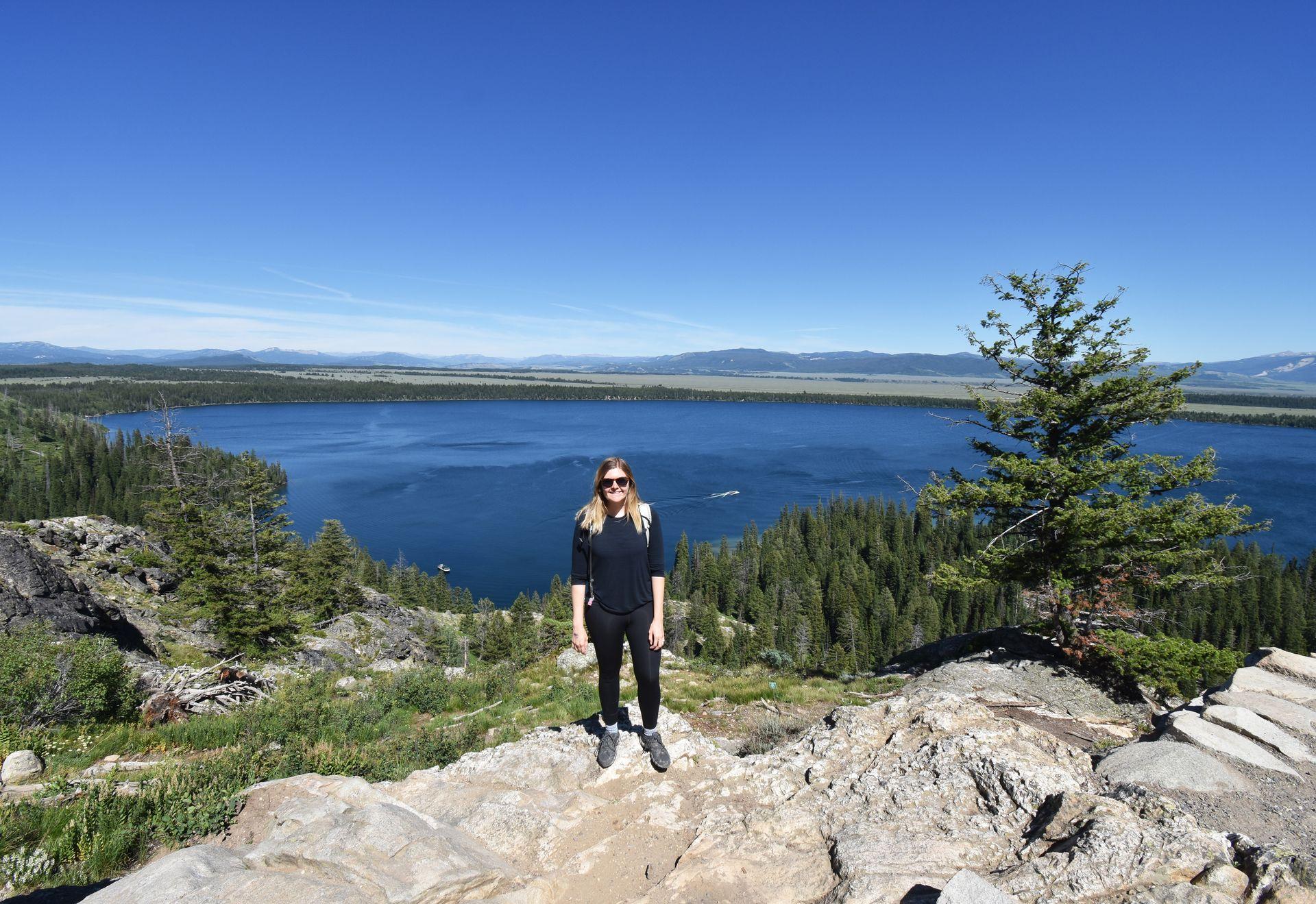 Lydia standing on a rock with the view from Inspiration Point behind her. It is a great view of Jenny Lake.