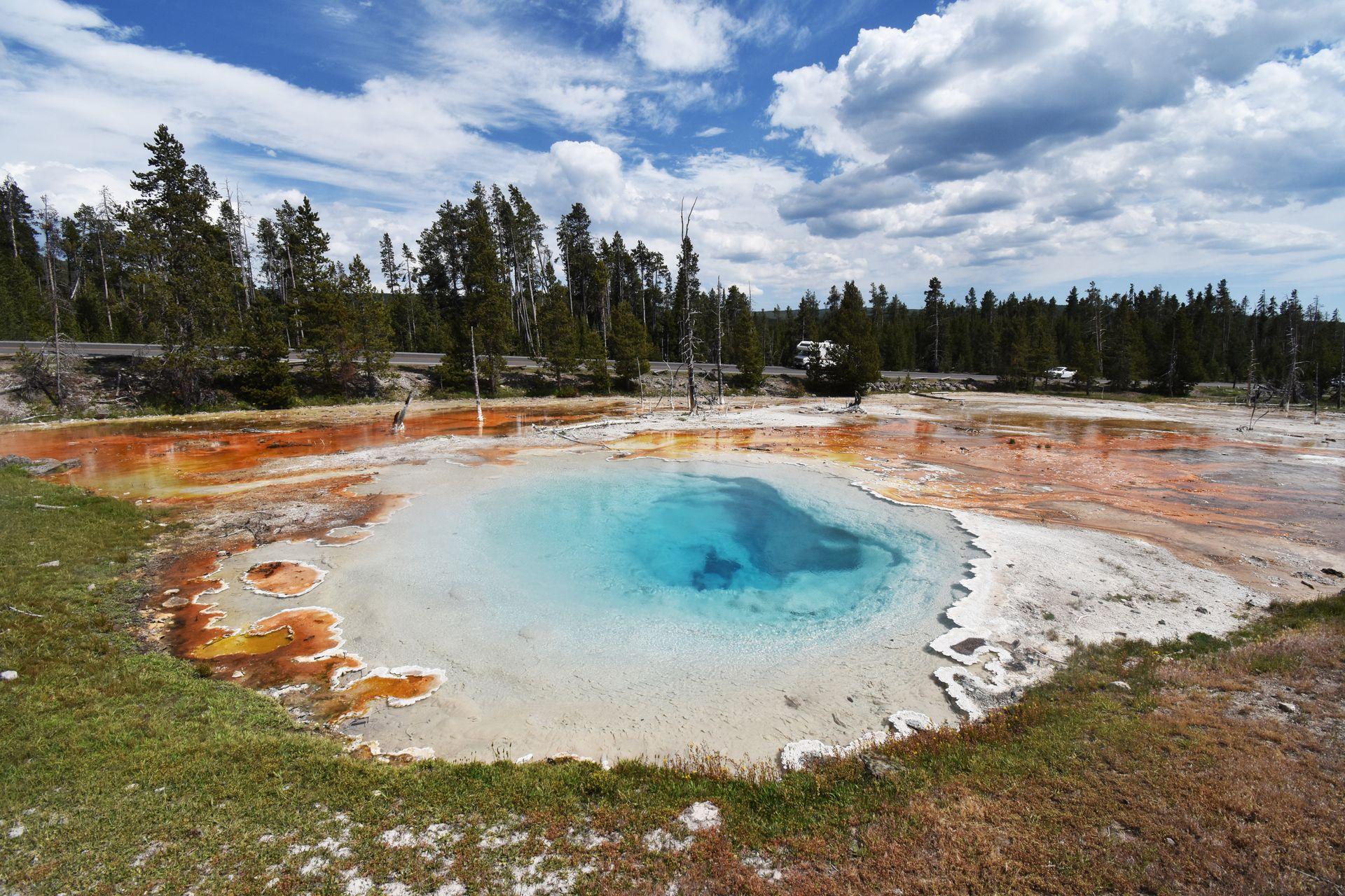 A bright blue spring surrounded by orange colors in the Fountain Paint Pots area of Yellowstone.