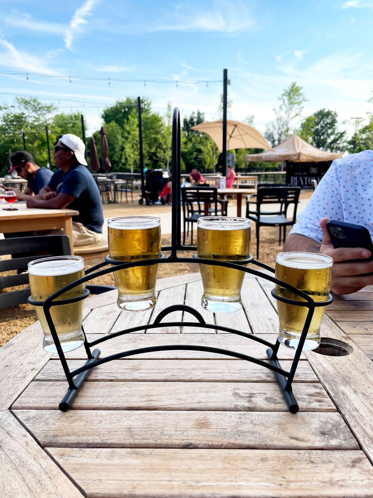 A flight of 4 beers sitting on an outdoor table.