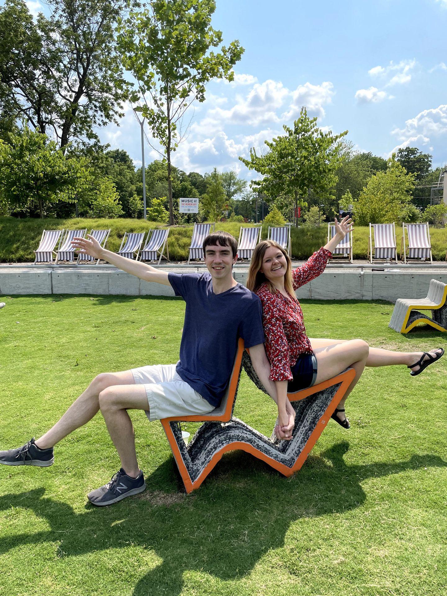 Lydia and Joe sitting on abstract-shaped chairs in the lawn outside of the Momentary
