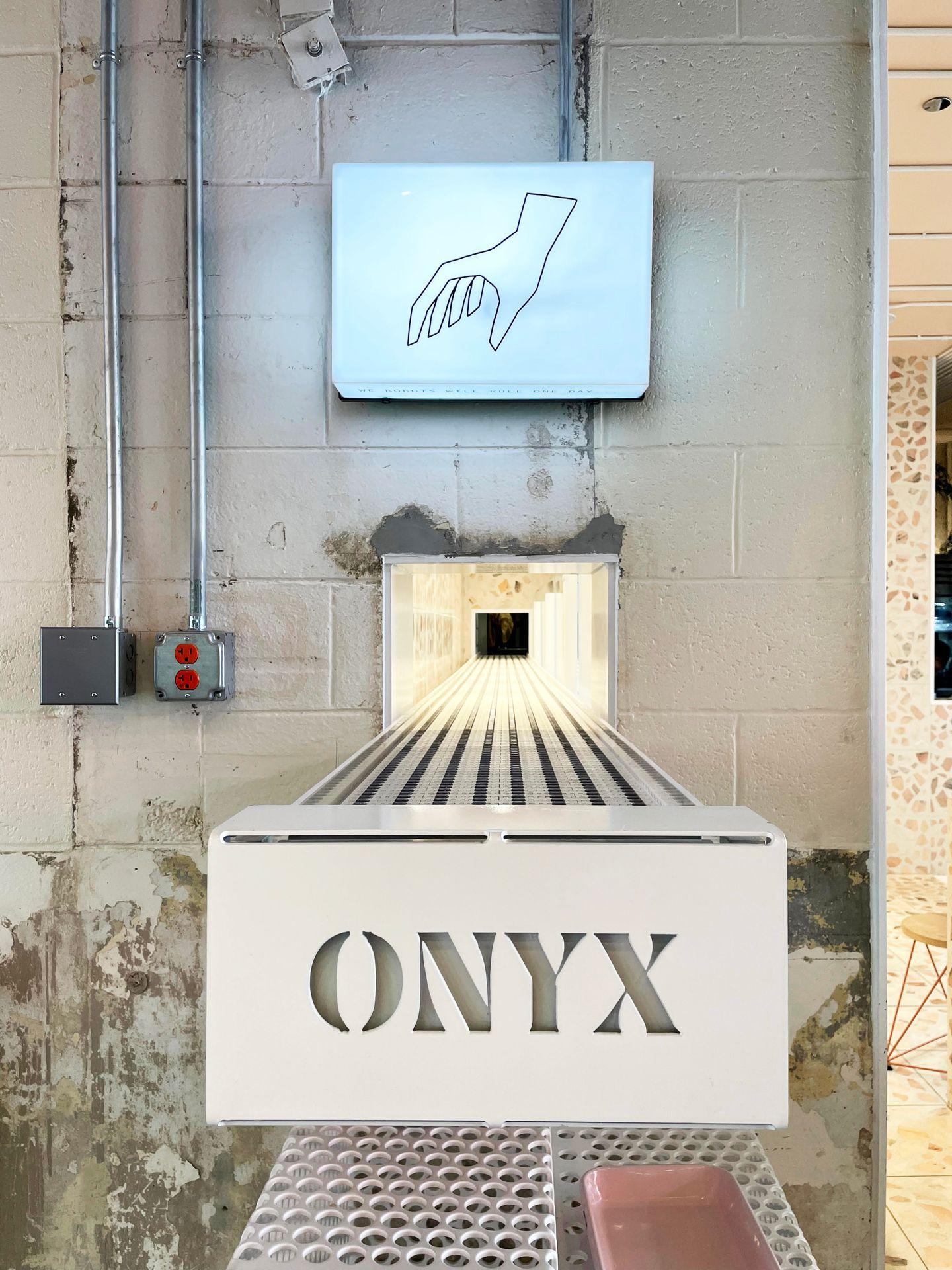 A conveyor belt with the word "onyx" on the end. There is an image of a hand above it.