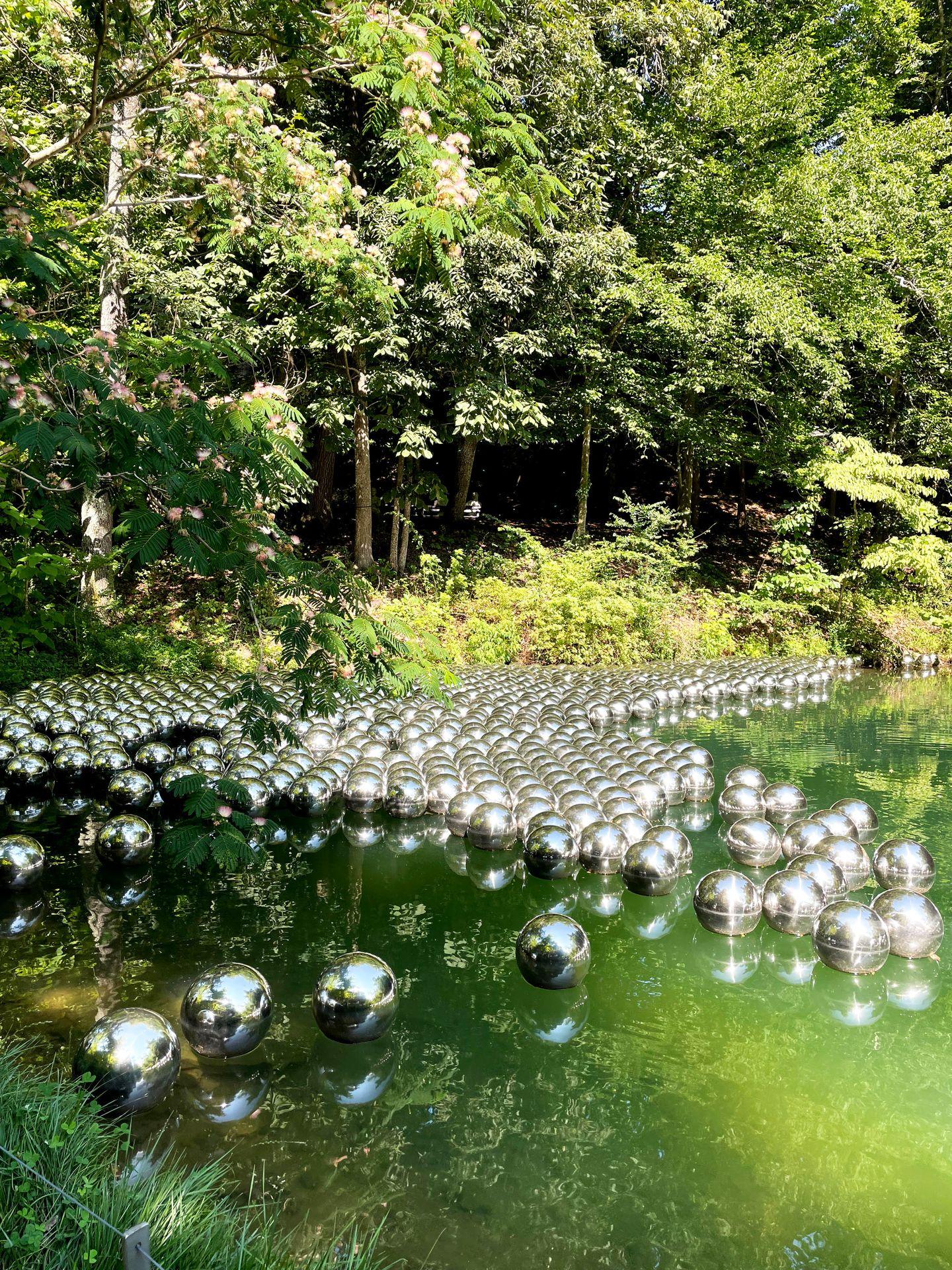 A pool of water with silver balls outside of Crystal Bridges.