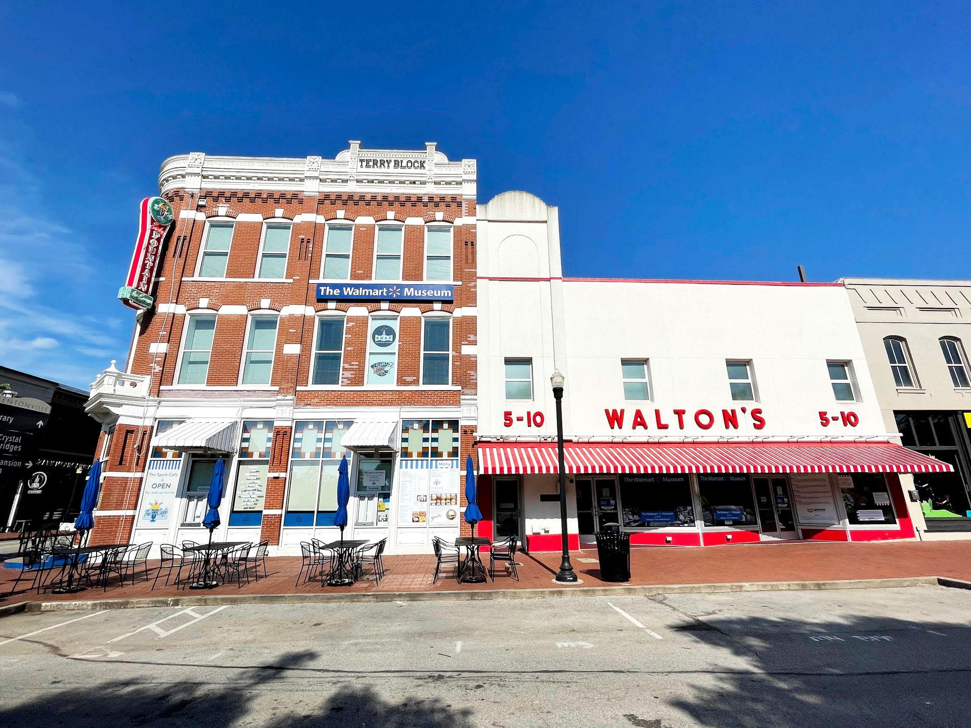 The exterior of the Walmart Museum and Walton's 5-10. The corner building is two stories tall made of brick, while Walton's is a white storefront with red letters.