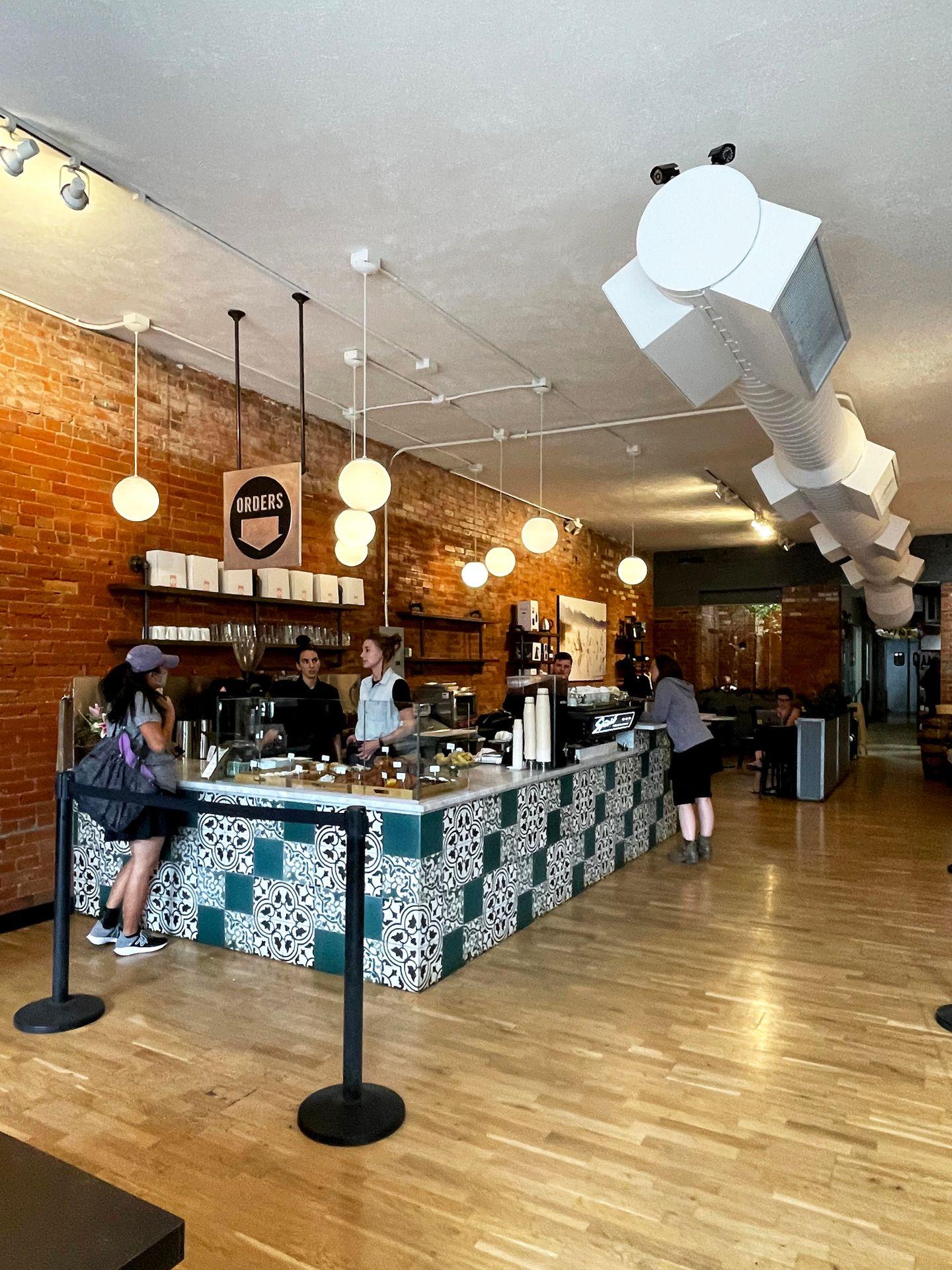 The interior of a coffee shop with wood floors and ceiling and blue and white tiled counter.