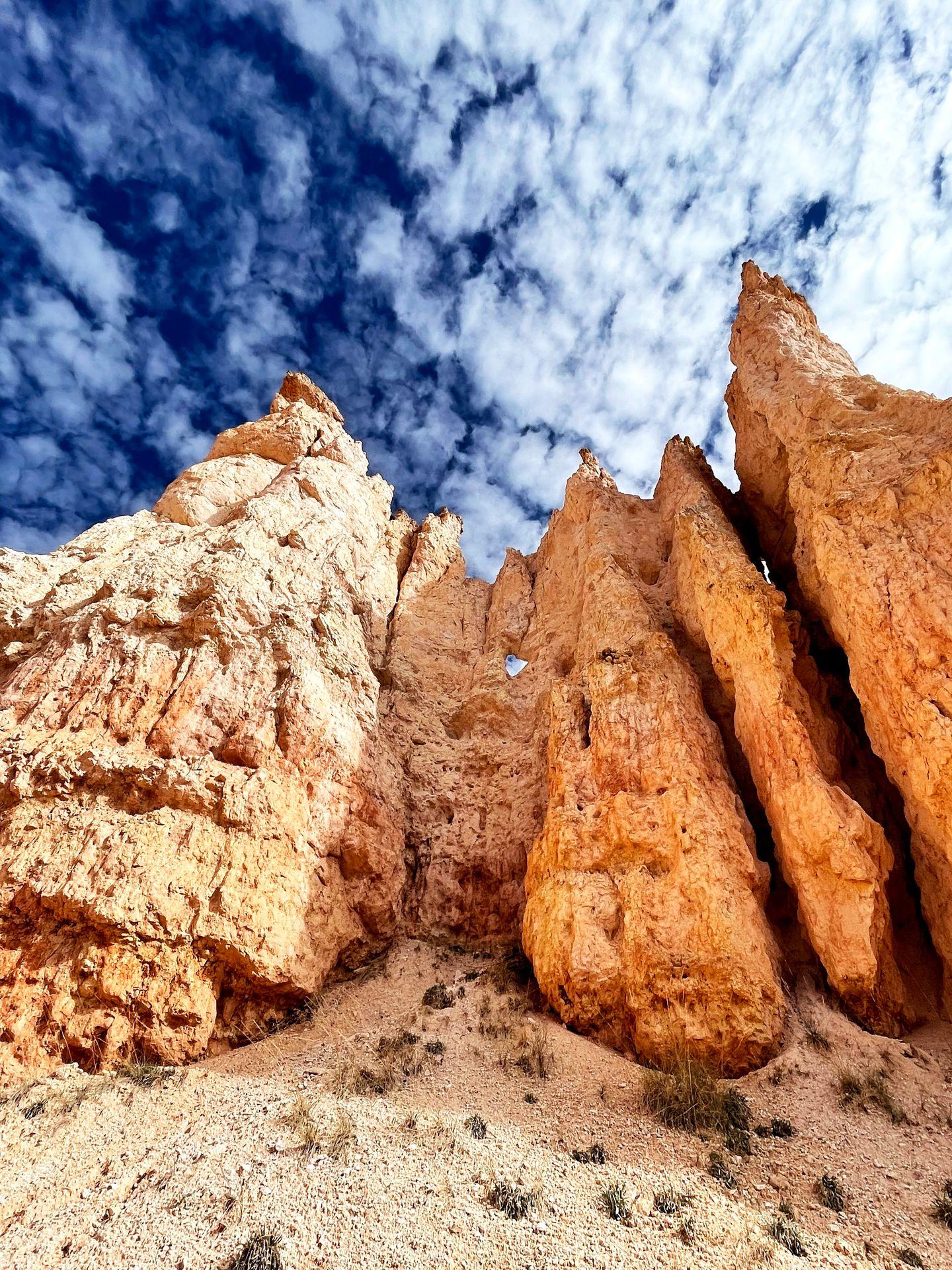 Looking up at hoodoo rock formations with a blue sky above them.
