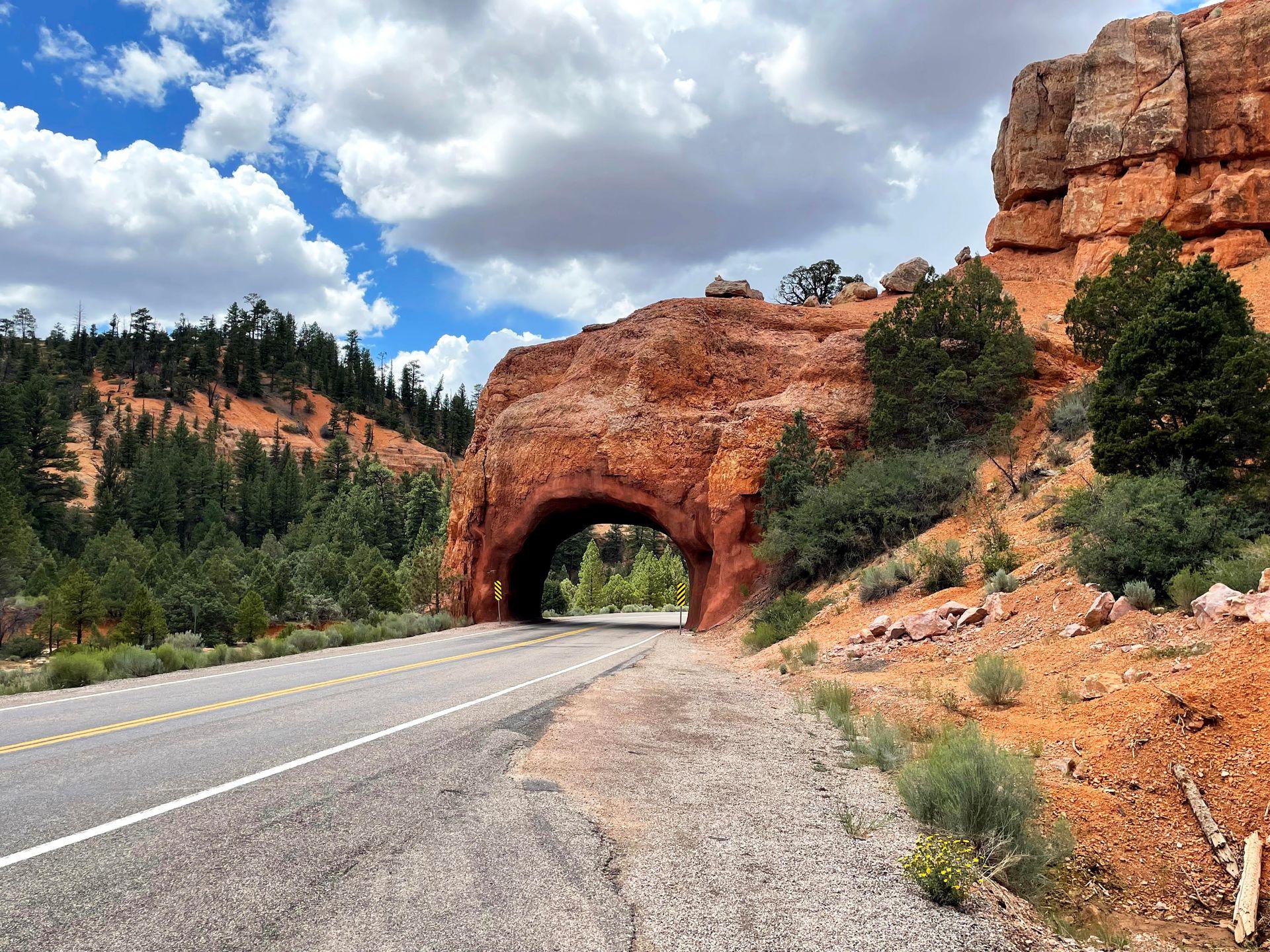 A orange rock tunnel that cars can drive through at Red Canyon.