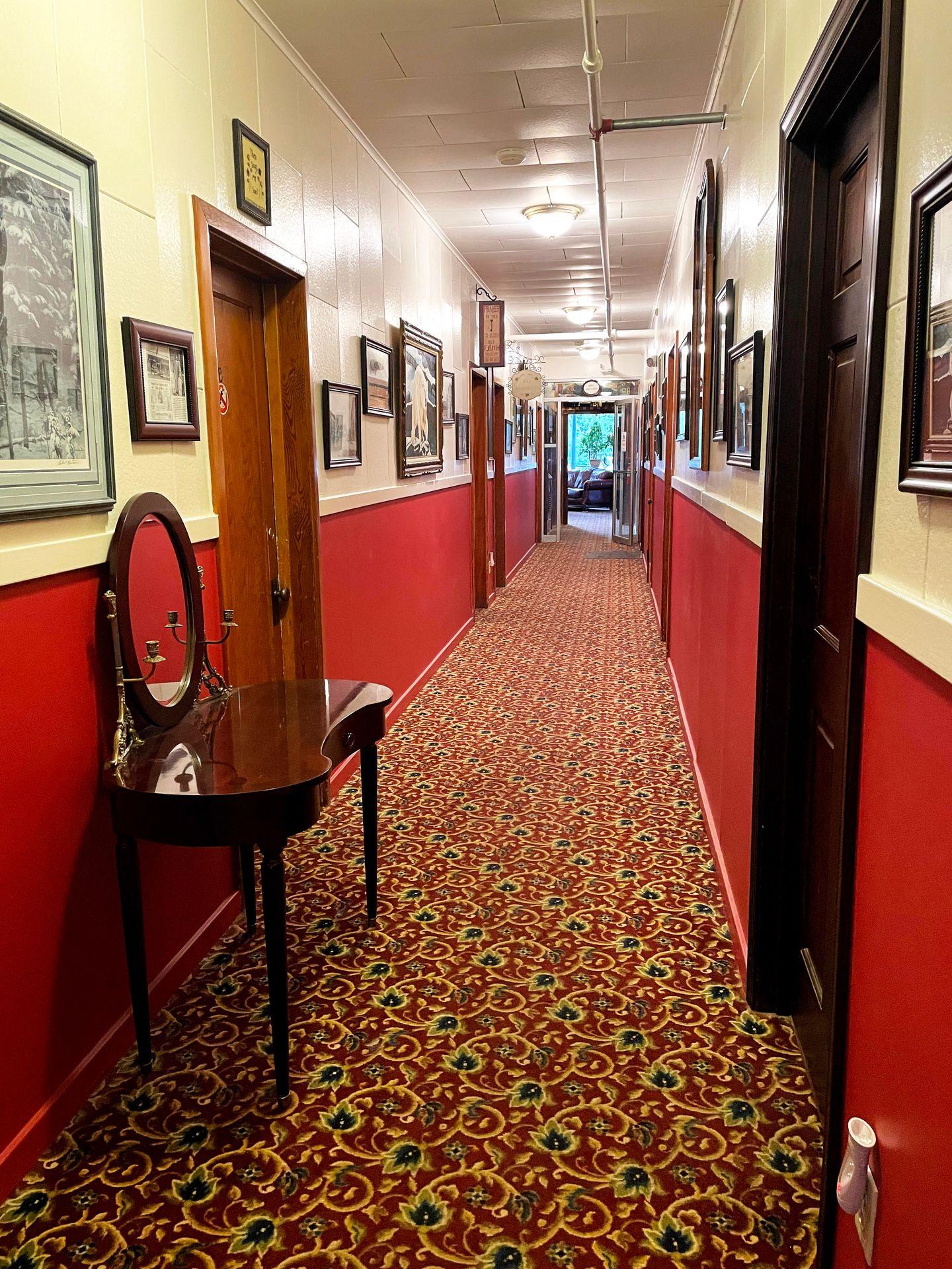 A hallway with red and cream walls inside of Hotel Seward.