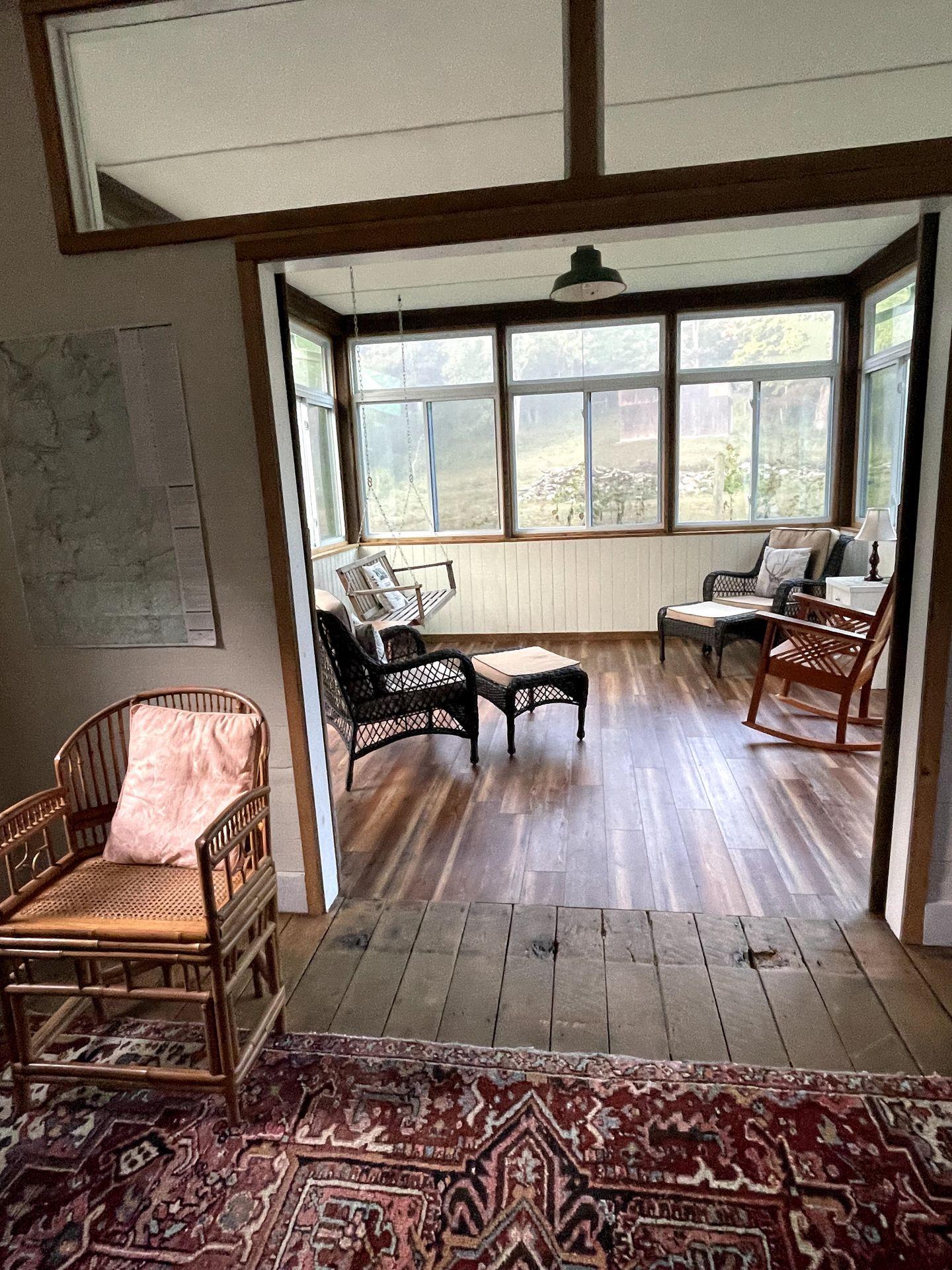 An interior photo of Five Springs Farm. There is a purple patterned rug, a floor of reclaimed wood and an ecletic mix of chairs.