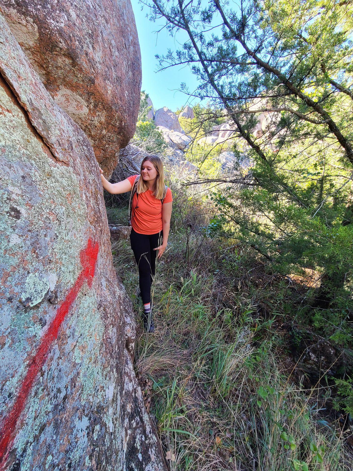 Lydia standing next to a spray prainted red arrow on the Eagle Mountain trail.
