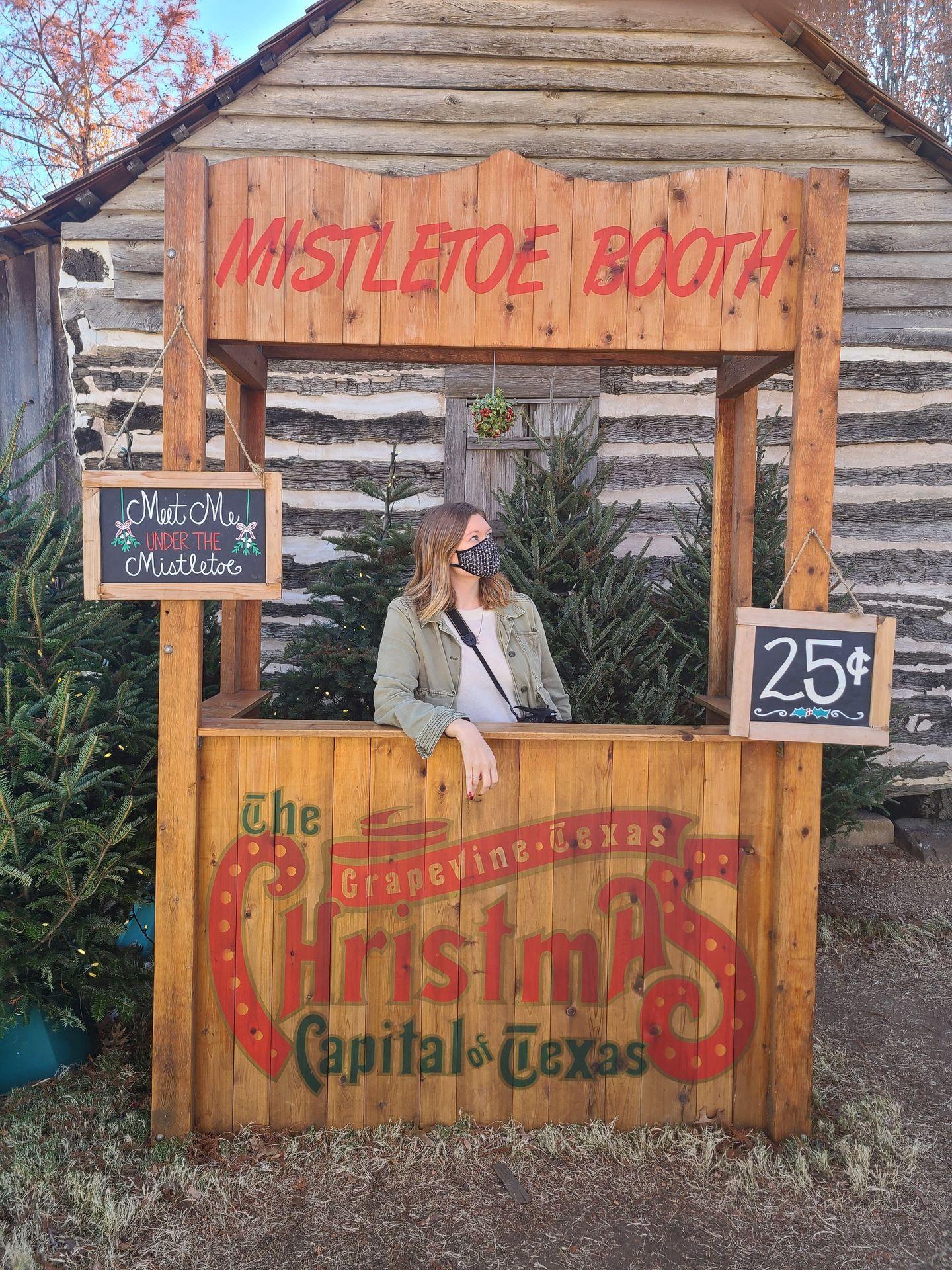 Lydia standing in a booth labeled "Mistletoe Booth" with a 25 cents price tag.