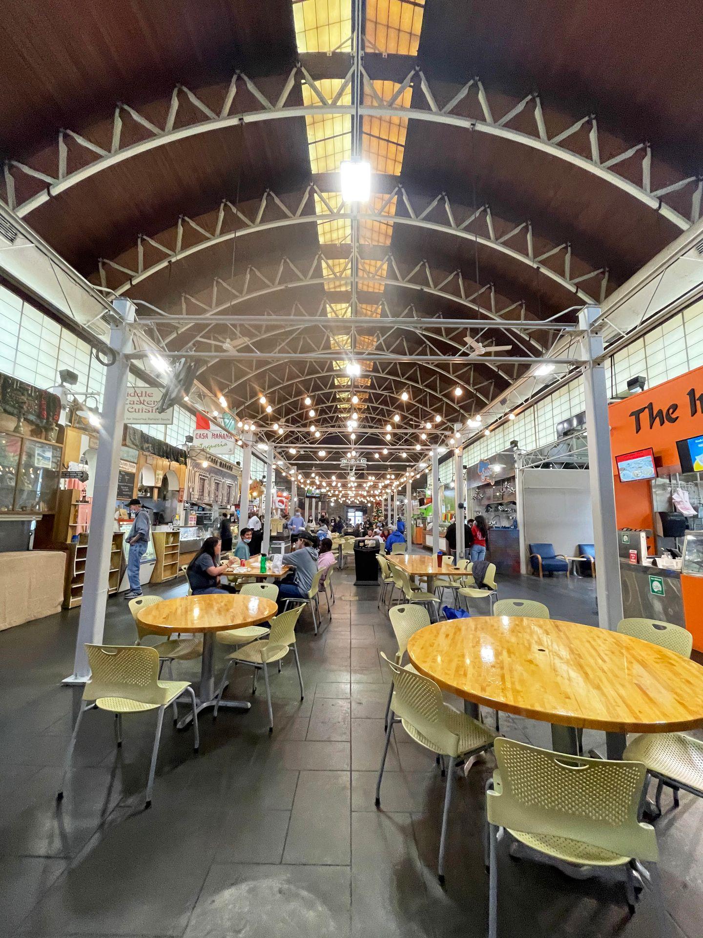 The inside of the Little Rock River Market. There are tables in the center, food vendors on the sides and an arch in the ceiling above.