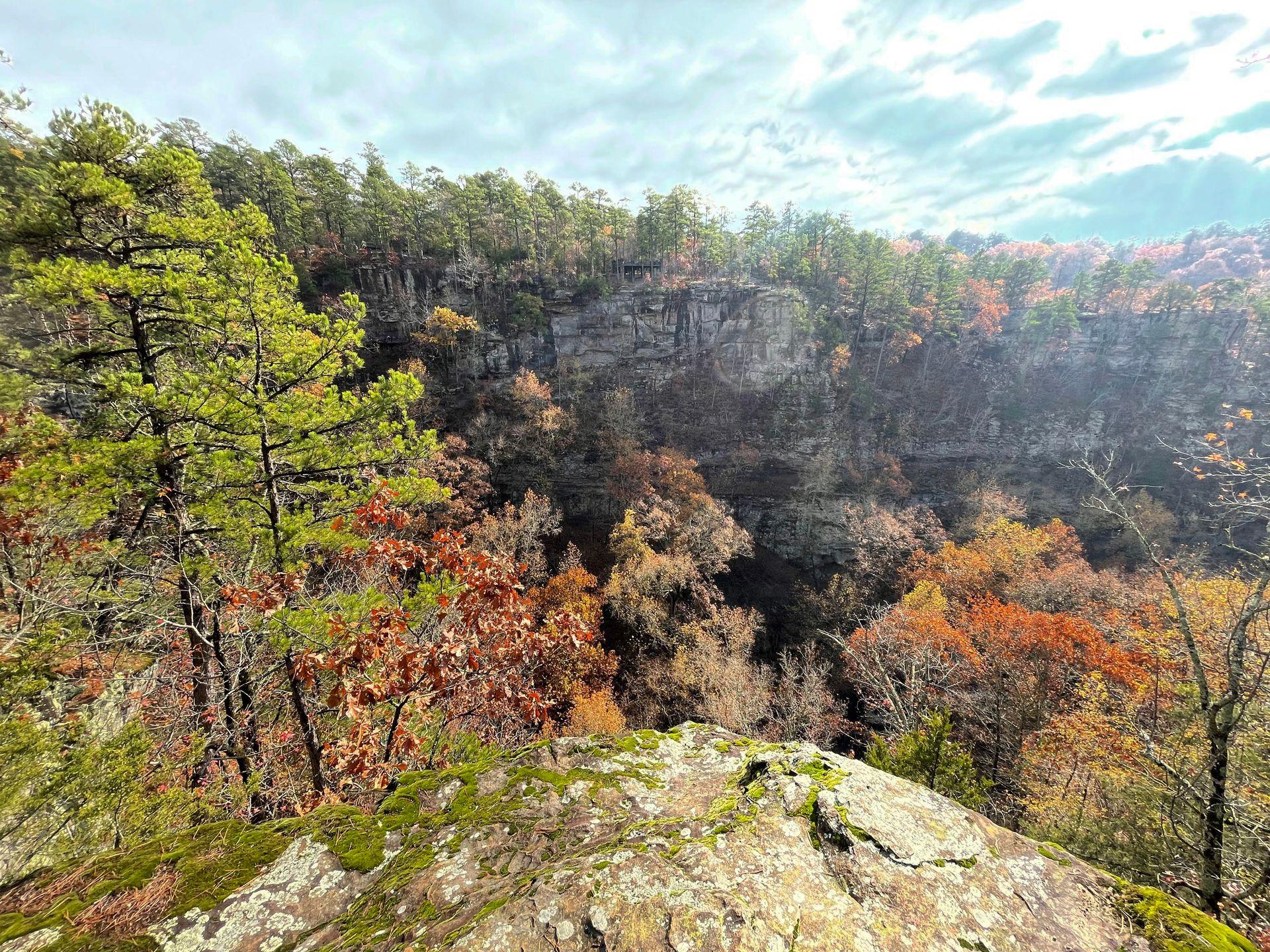 A view of a rock face surrounded by trees in colorful fall foliage.