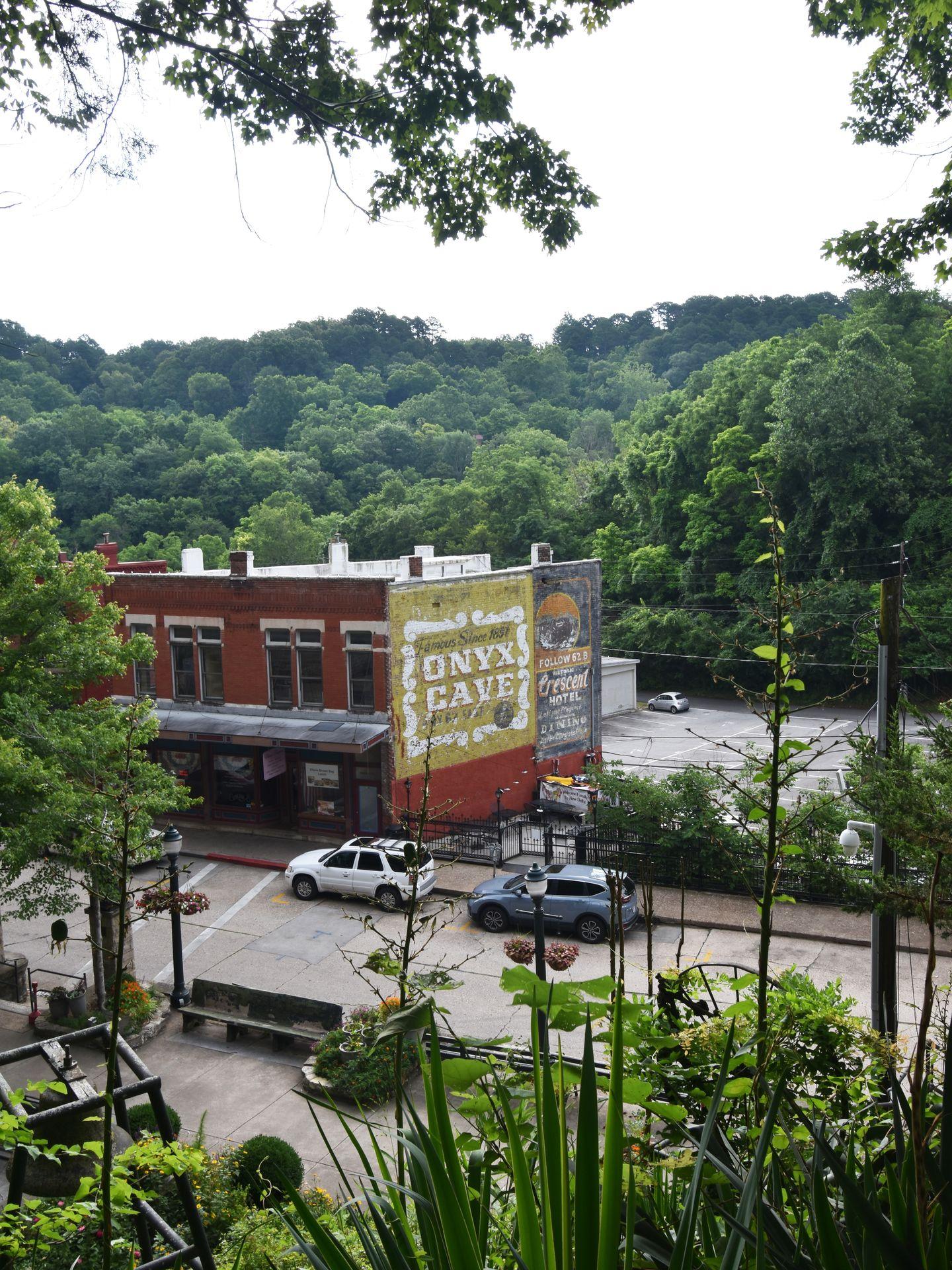 Looking down at some buildings in downtown Eureka Springs. There is a big mural that reads "Onyx Cave."