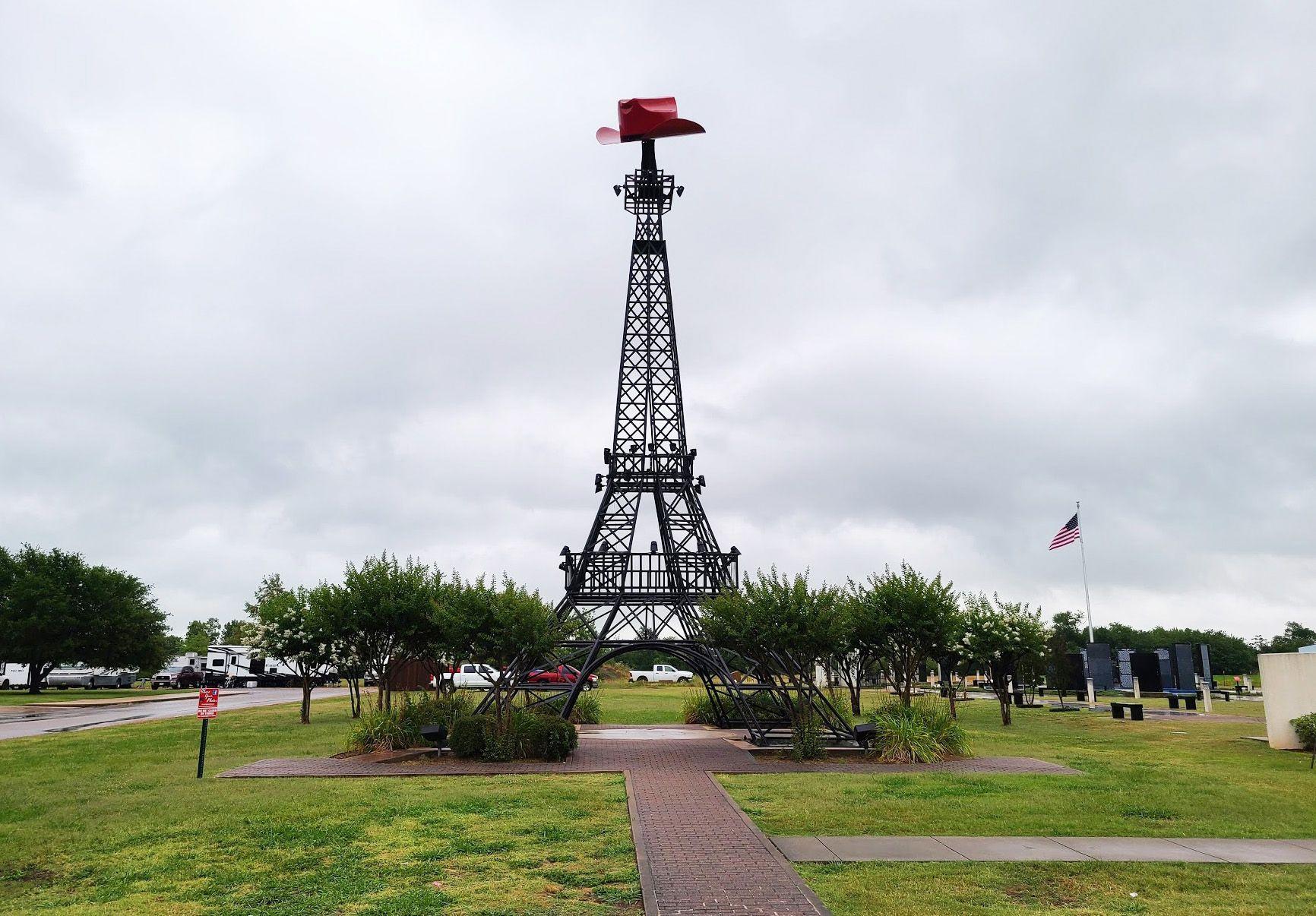 A small eiffel tower replica with a red cowboy hat on top.