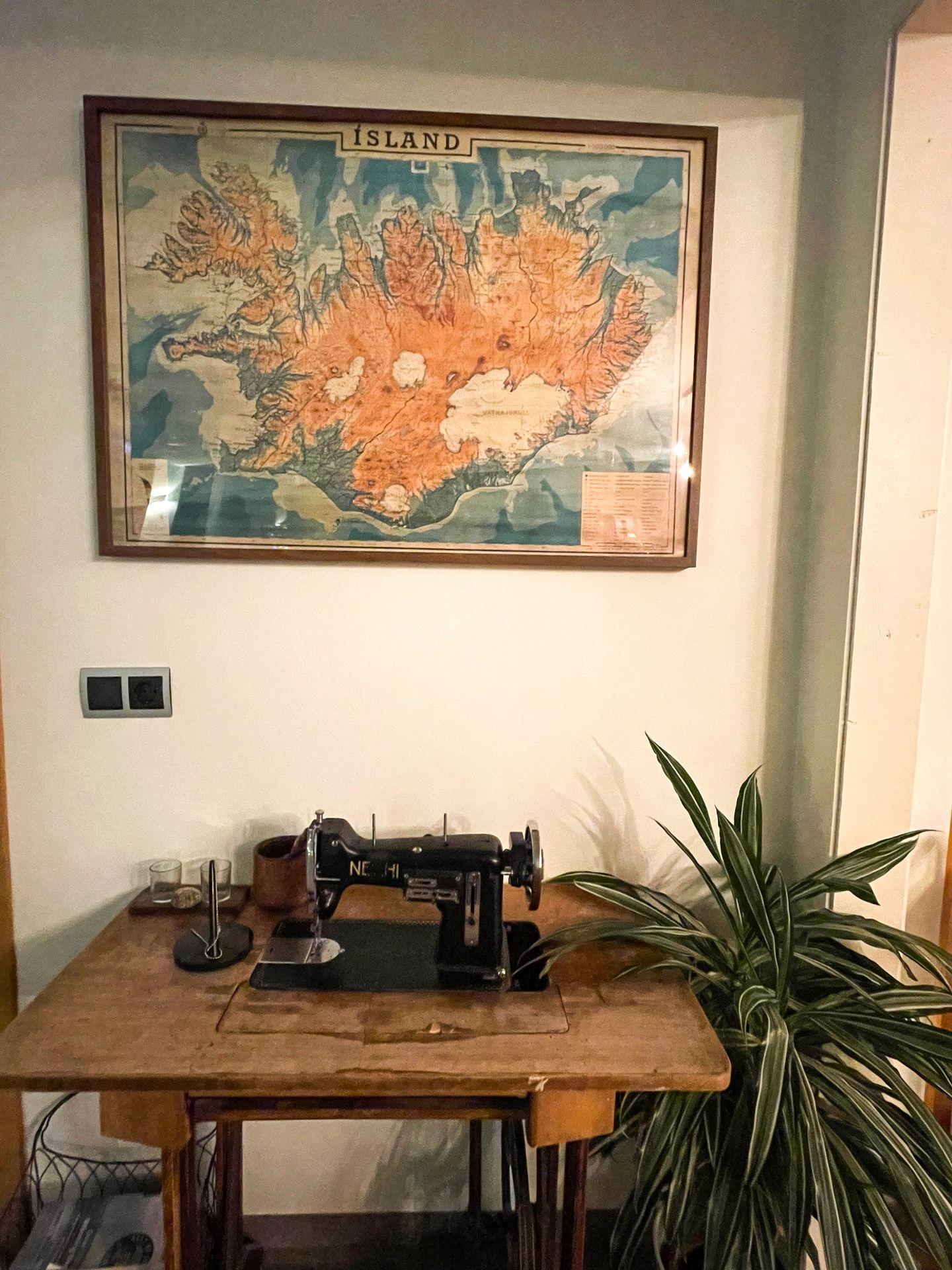 A vintage sewing machine with a map on the wall in the Héraðsskólinn Historic Guesthouse