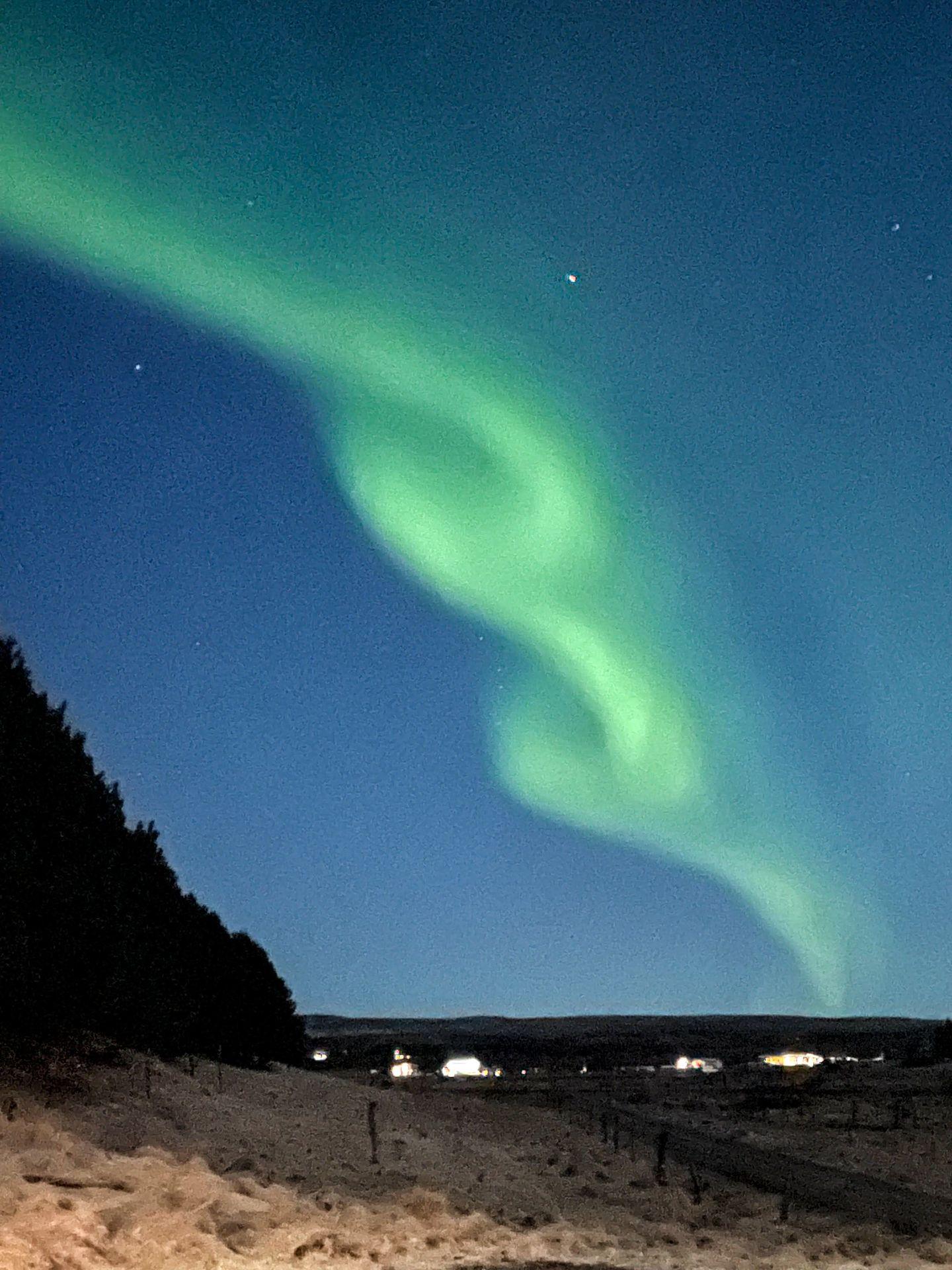 A green display of the Northern Lights. The lights twist around in a way that looks like a rope.