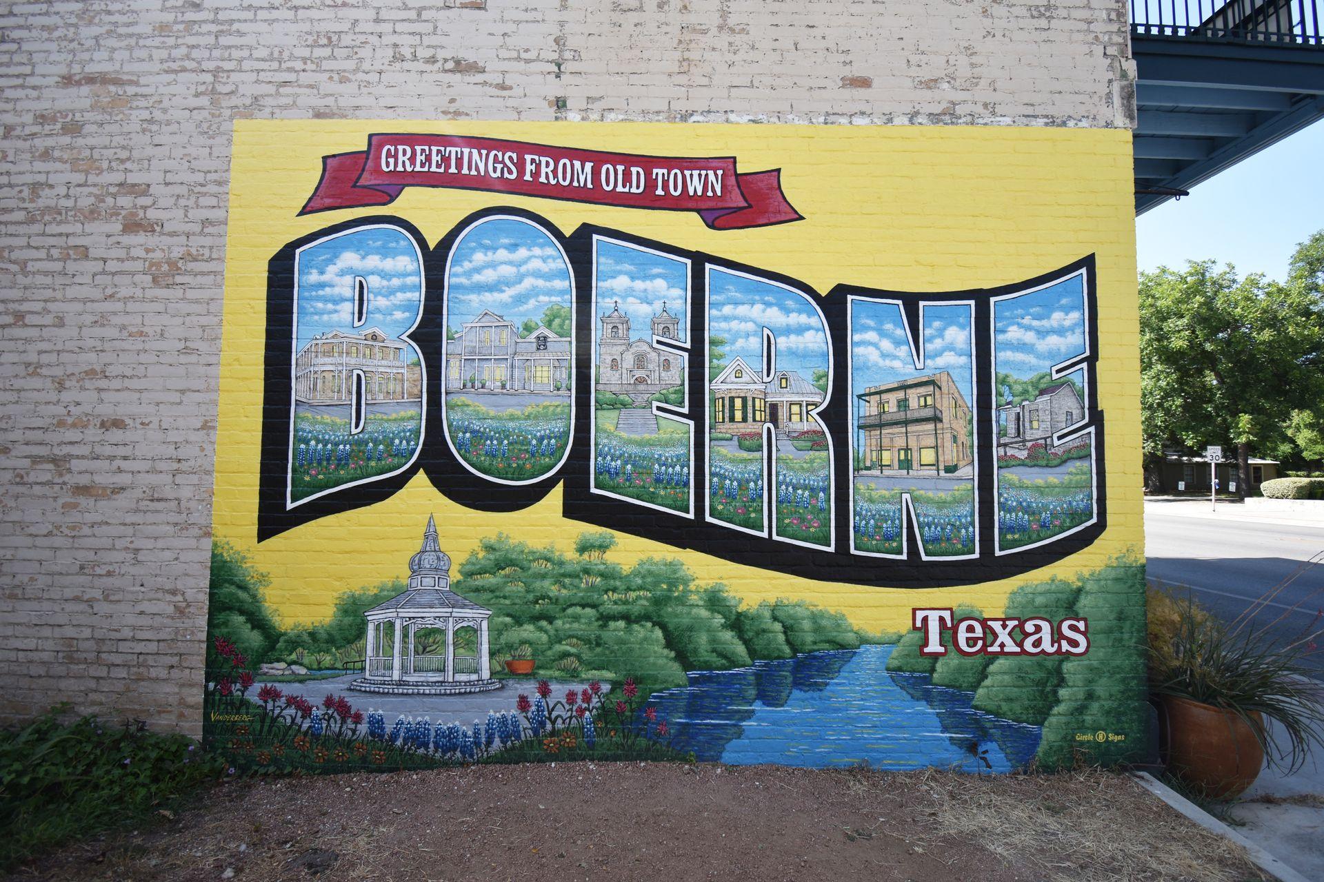 A mural of the word Boerne with a scene of buildings and flowers painted inside of the letters.