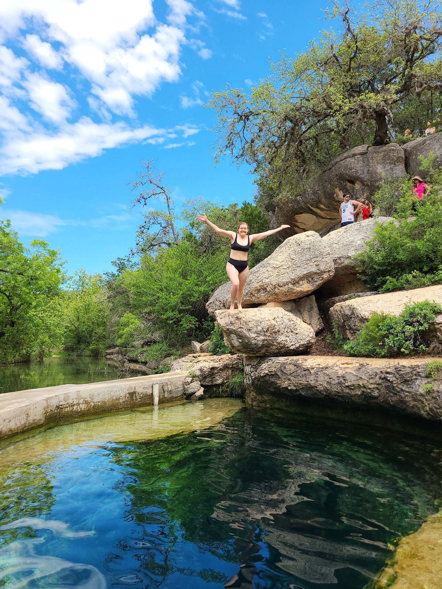 A view of Lydia about to jump into Jacob's Well from the ground.
