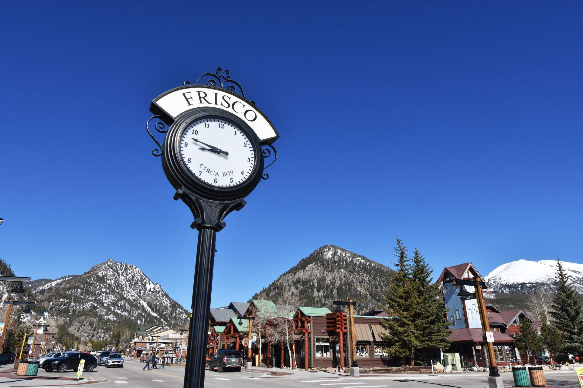 A clock in the town of Frisco with mountains in the background.