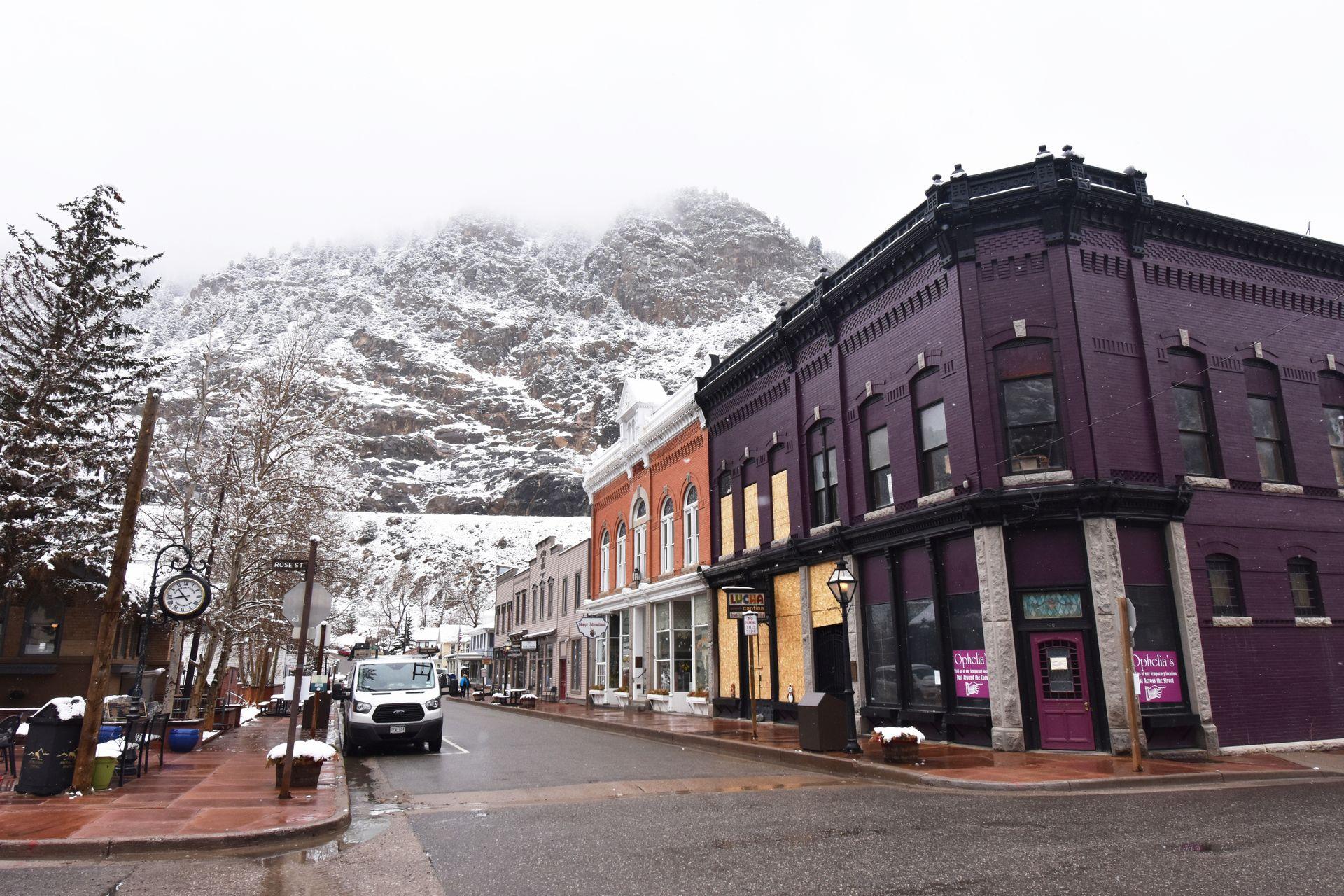 A purple building on a street corner in Georgetown. There are snow covered mountains in the background.