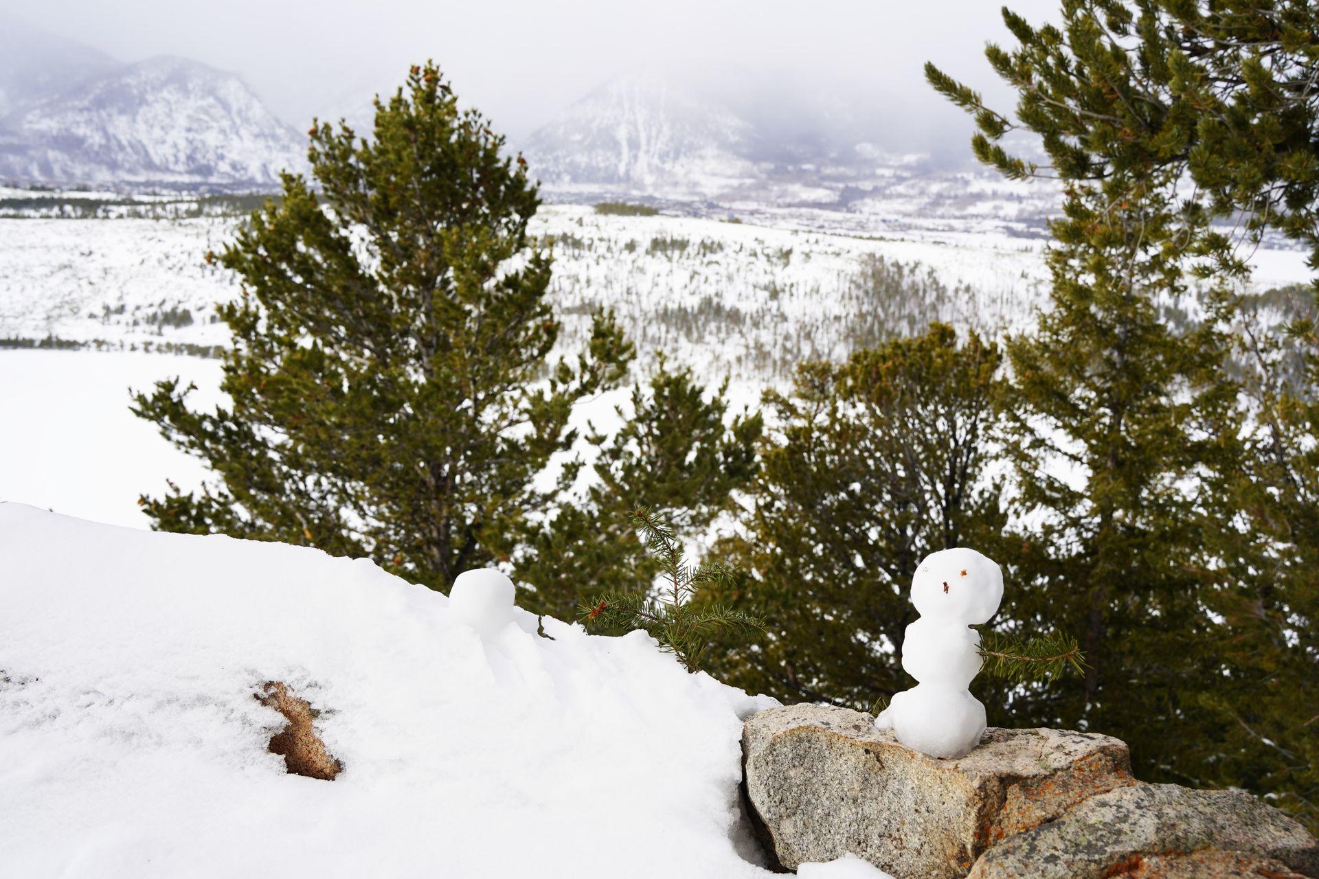 A mini snowman sitting on a rock with the Sapphire Point Overlook view in the background.