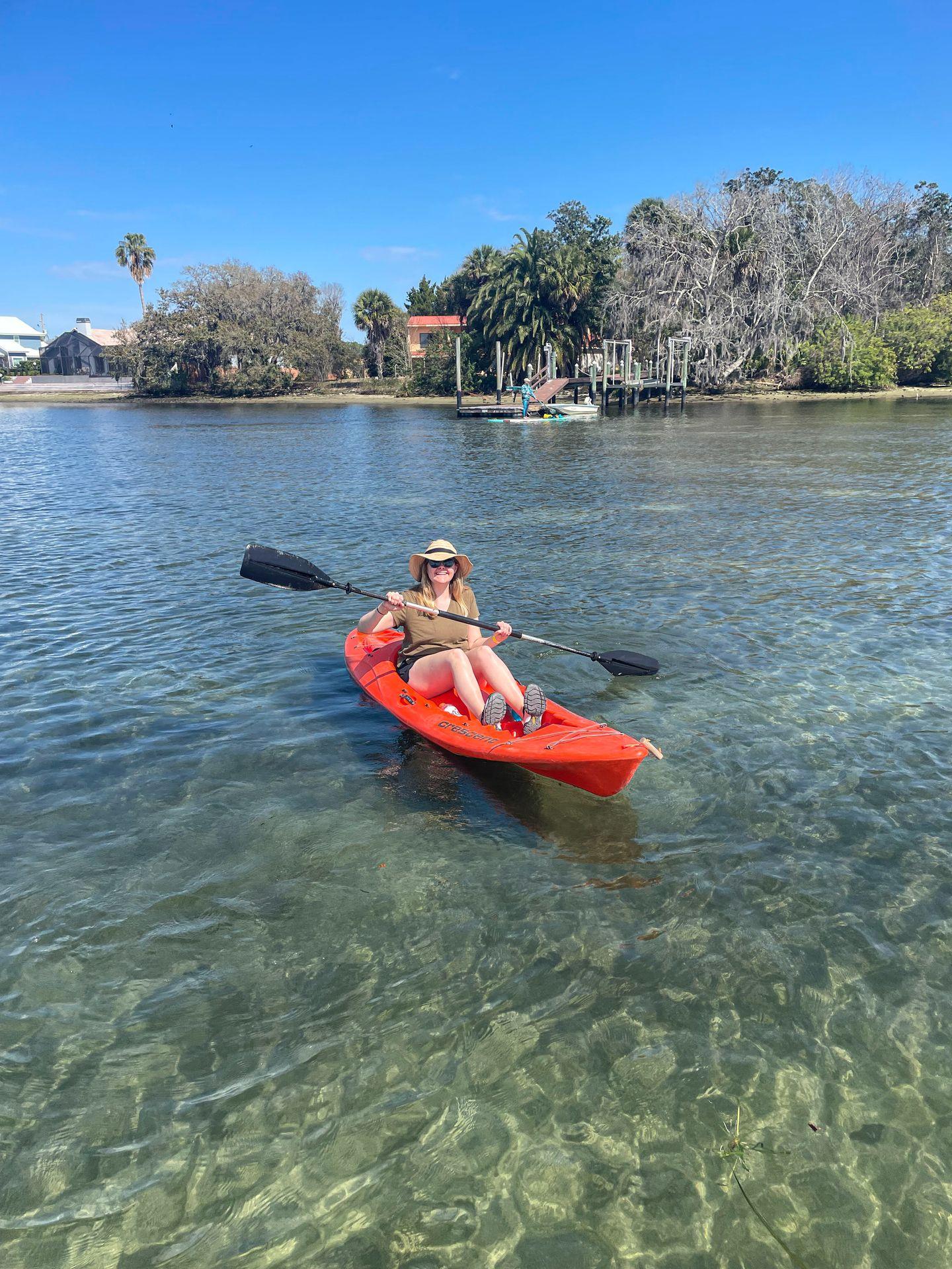 Lydia sitting on a red kayak in Crystal River.