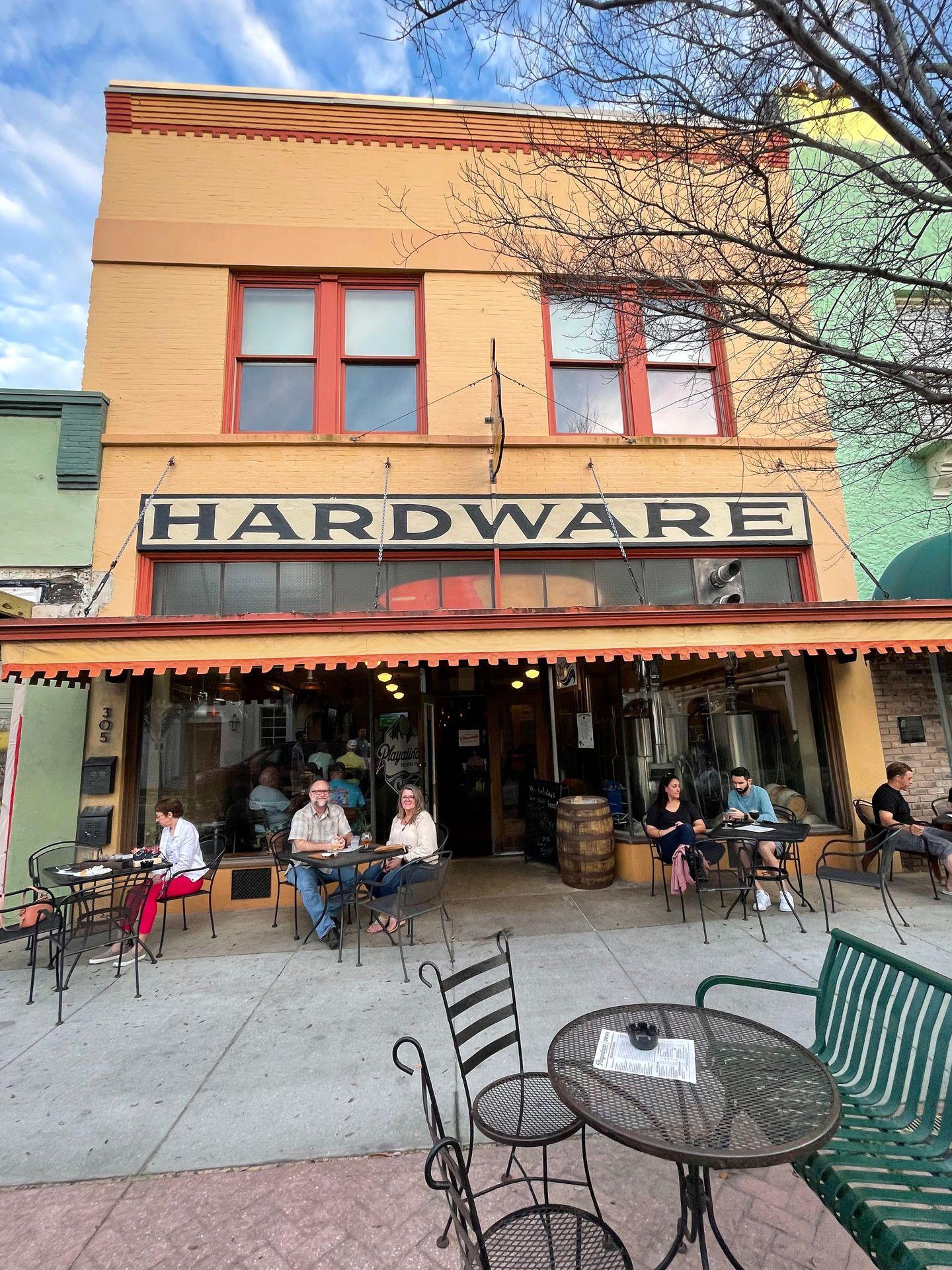 A yellow building labeled 'hardware' with tables out front.