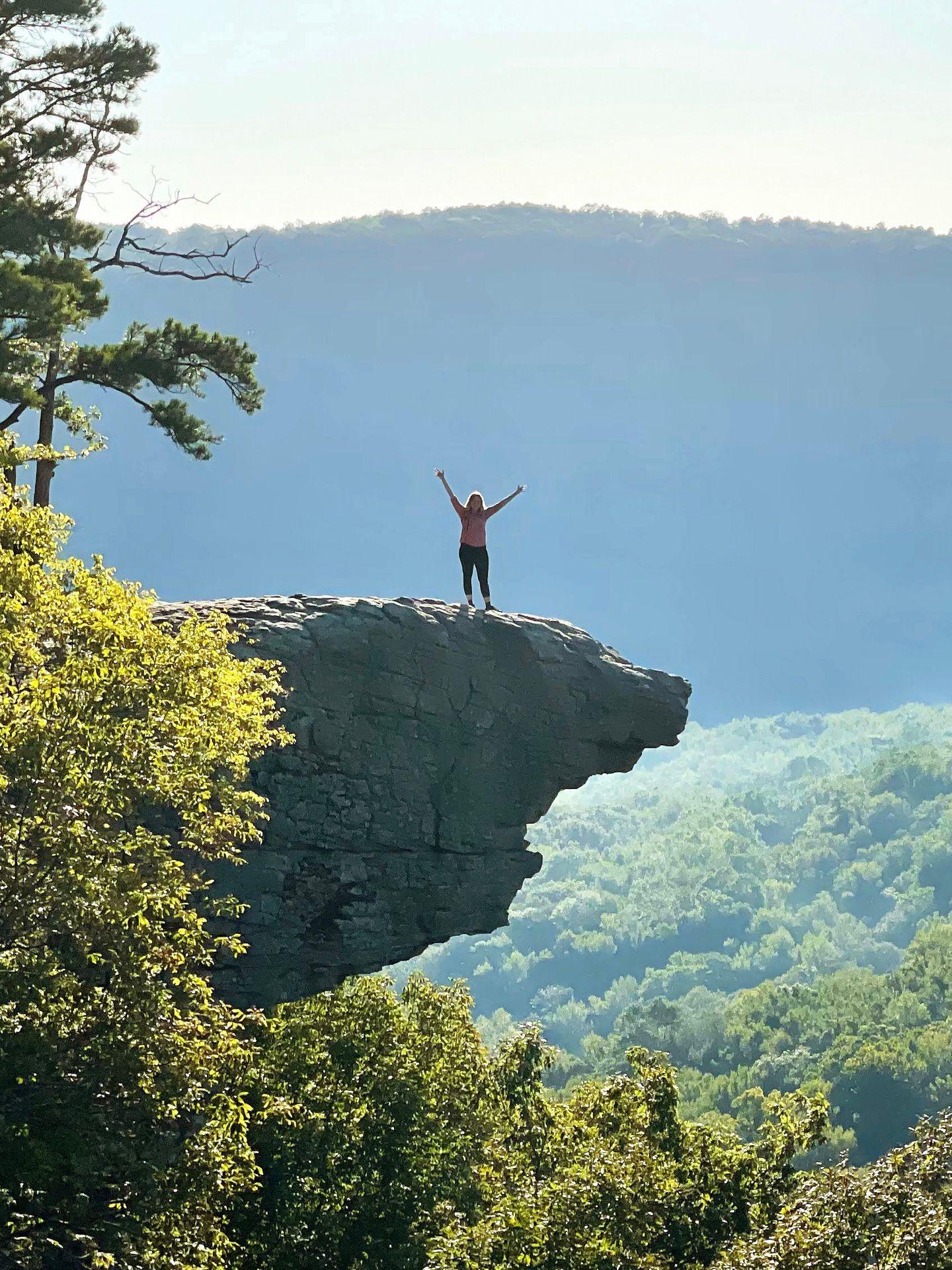 Lydia stands on the Whitaker Point rock with her hands in the air.