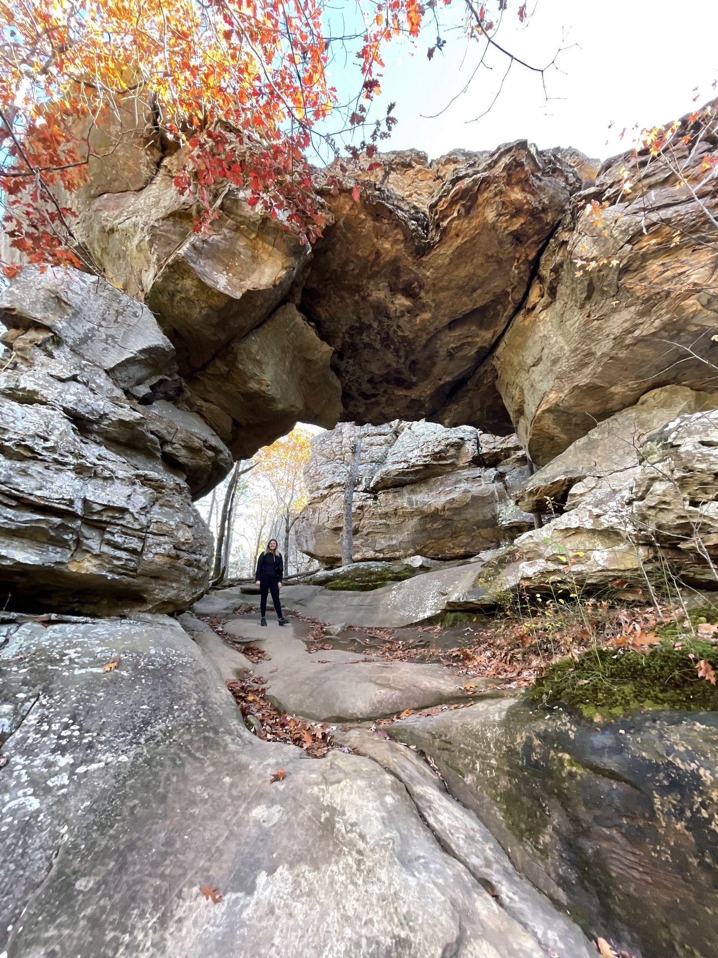 Lydia stands underneath a rock arch on the Seven Hollows trail in Petit Jean State Park.