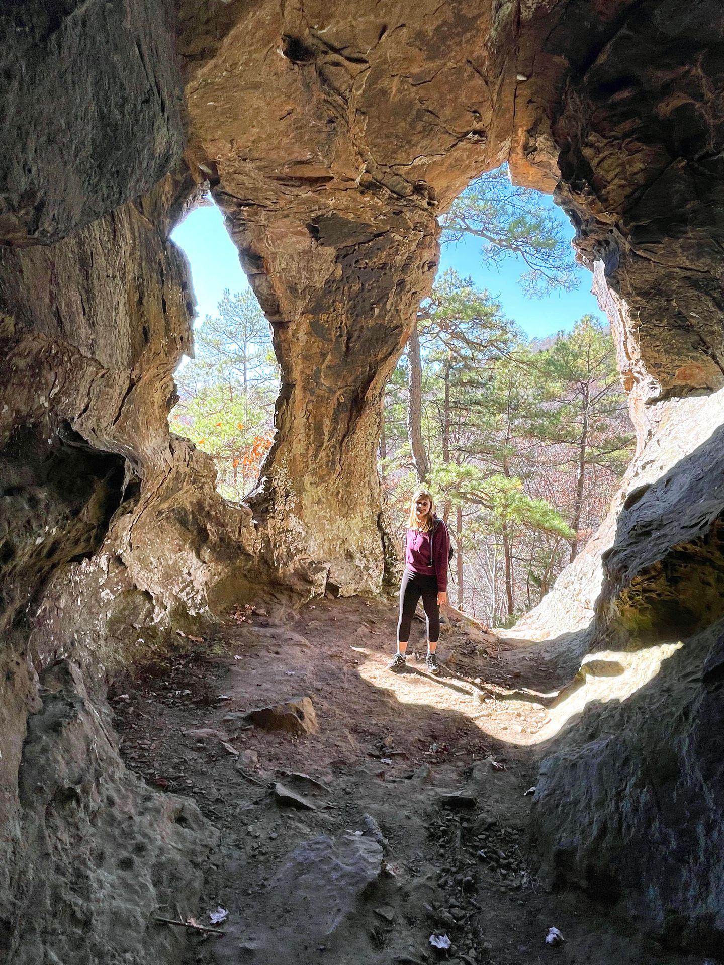 Lydia standing in a cave with two rock arch openings behind her.