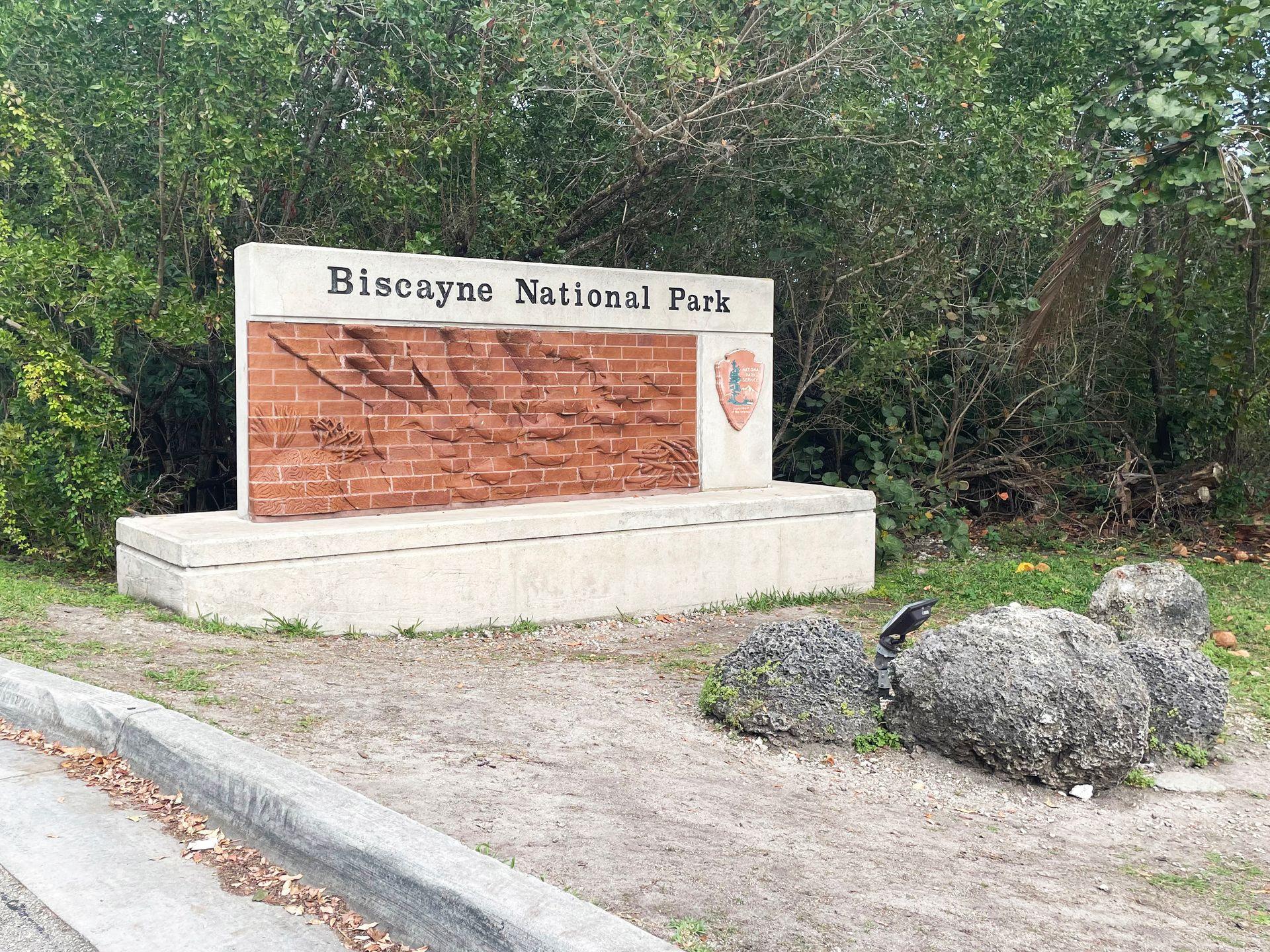 A large Biscayne National Park sign at the entrance of the park. The sign includes a scene of fish made of bricks