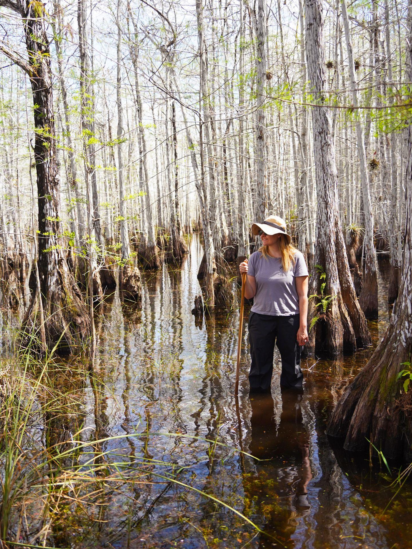 Lydia standing knee deep in water surrounded by white cypress trees.