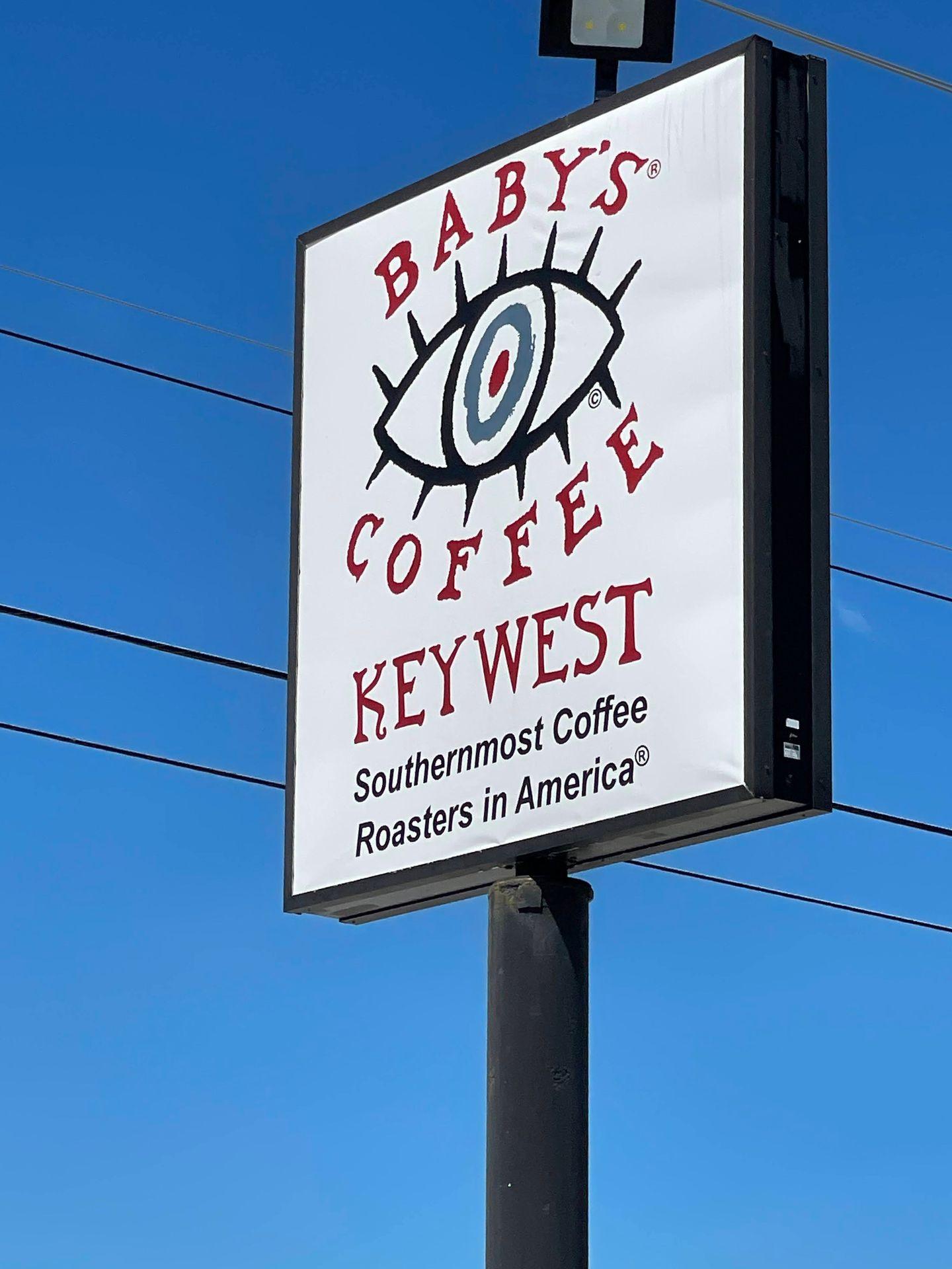 A Baby's Coffee sign outdoors with the tagline 'Southernmost Coffee Roasters in America'