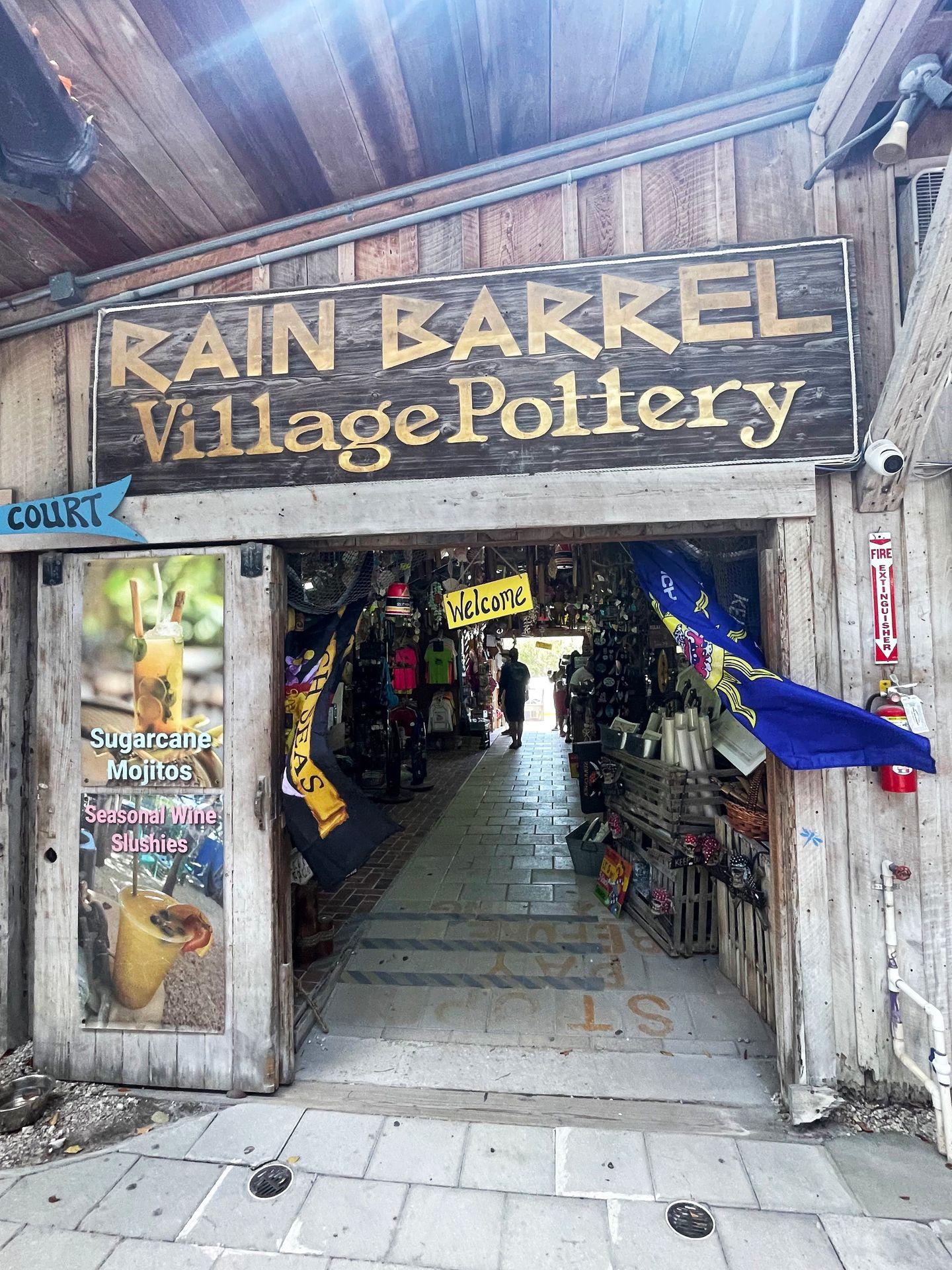 A doorway with a "Rain Barrel Artisan Village" sign above it. The door leads into a giftshop.