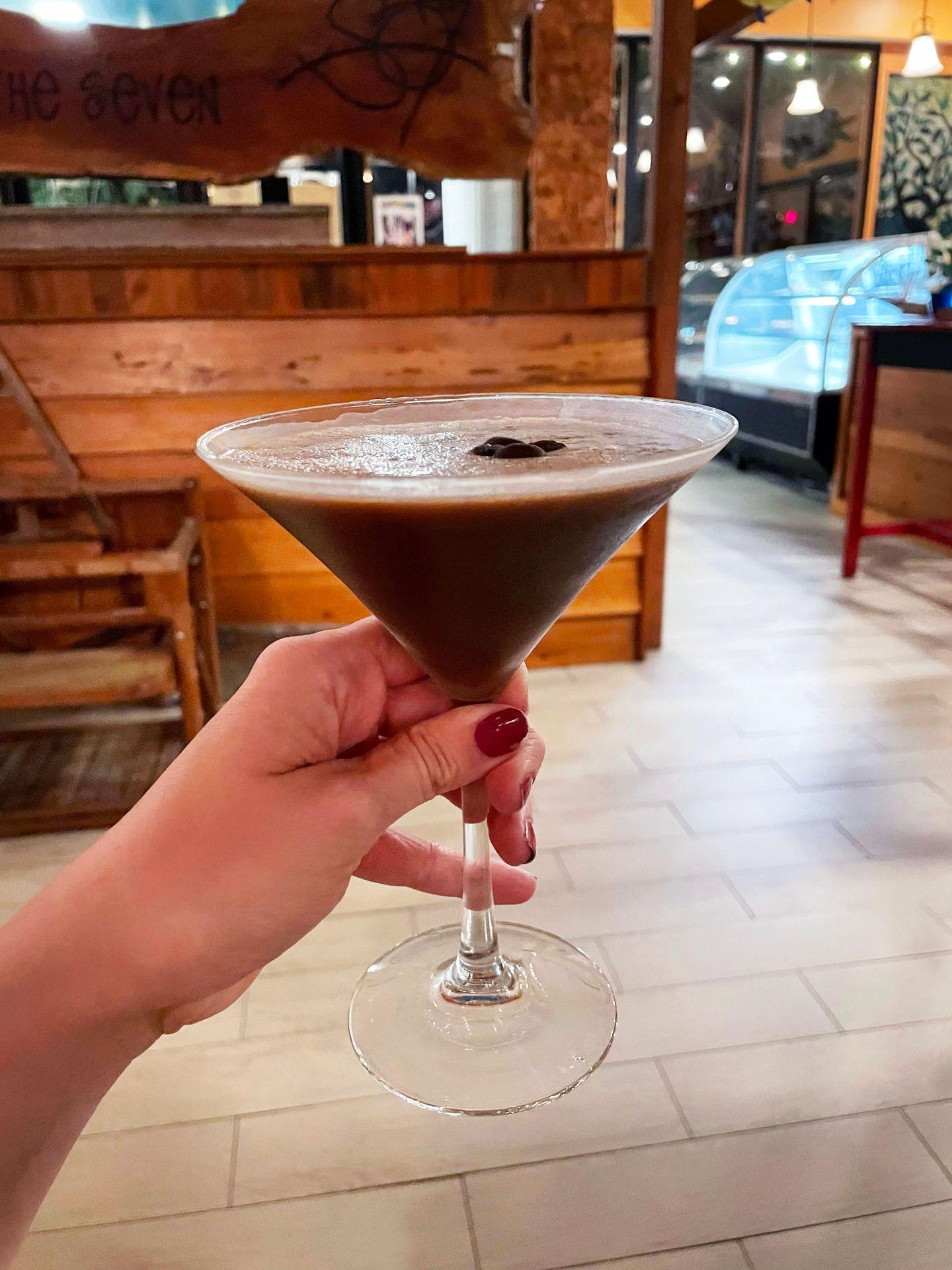 A chocolate espresso martini being held up at South of the Seven
