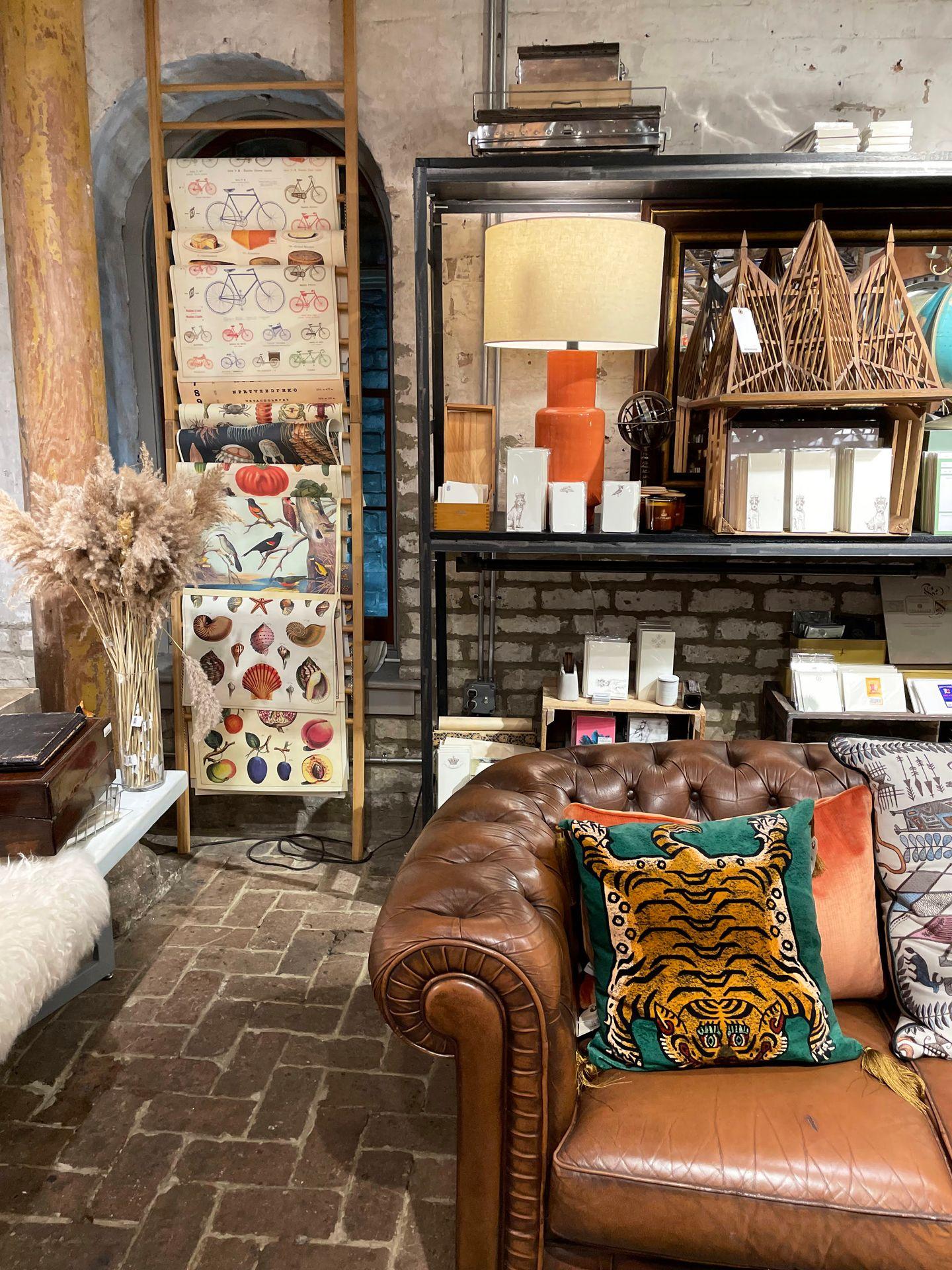 The interior of the Paris Market boutique. There is a brown couch with pillows, lights and artwork in the background.