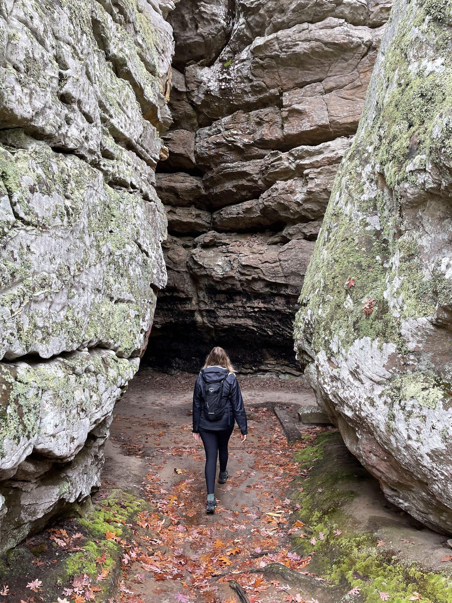 Lydia walking between tall, rock faces in the Bear Cave area at Petit Jean State Park.