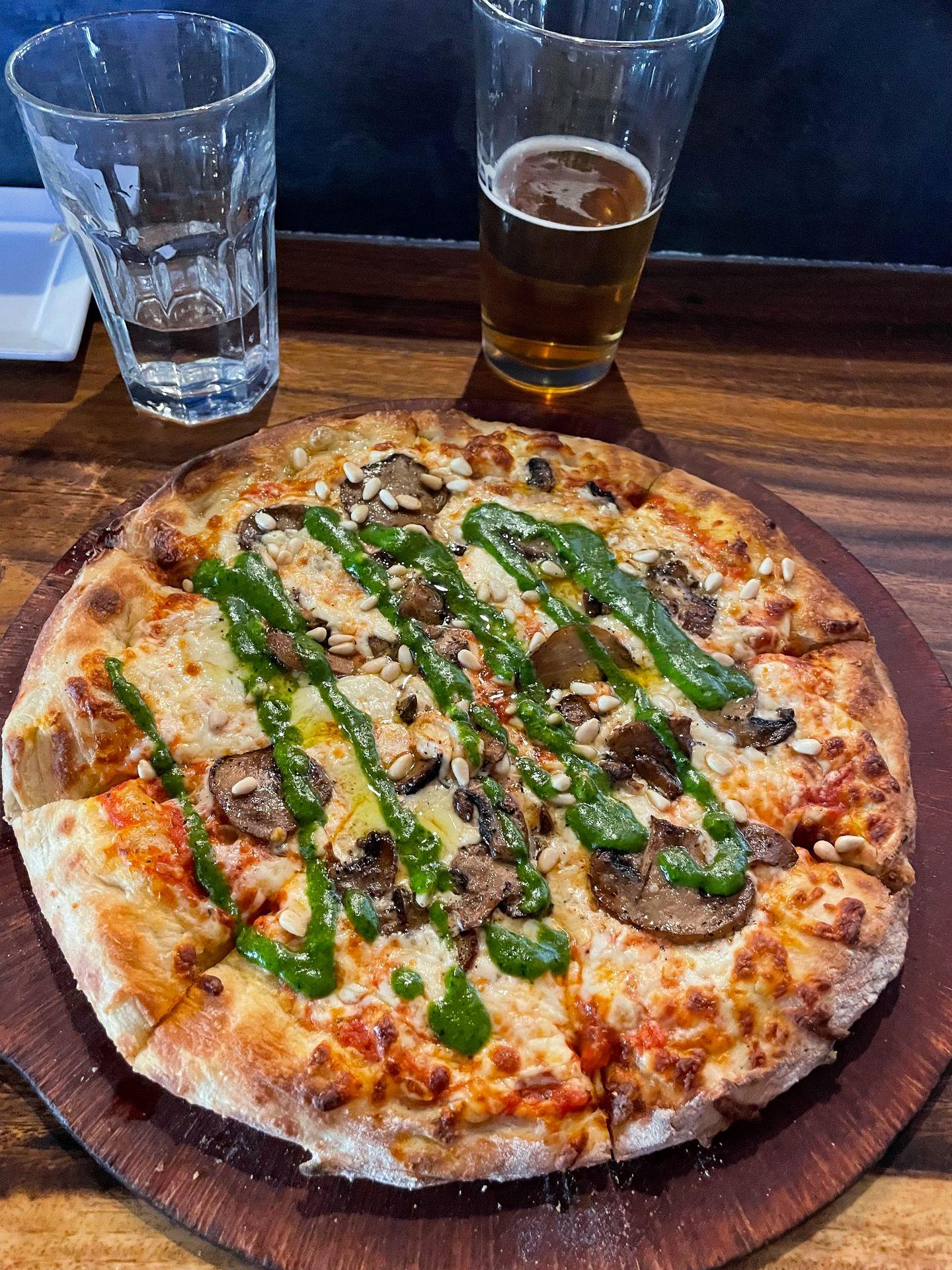 A pizza drizzled with pesto and topped with mushrooms from Bear Street Tavern.