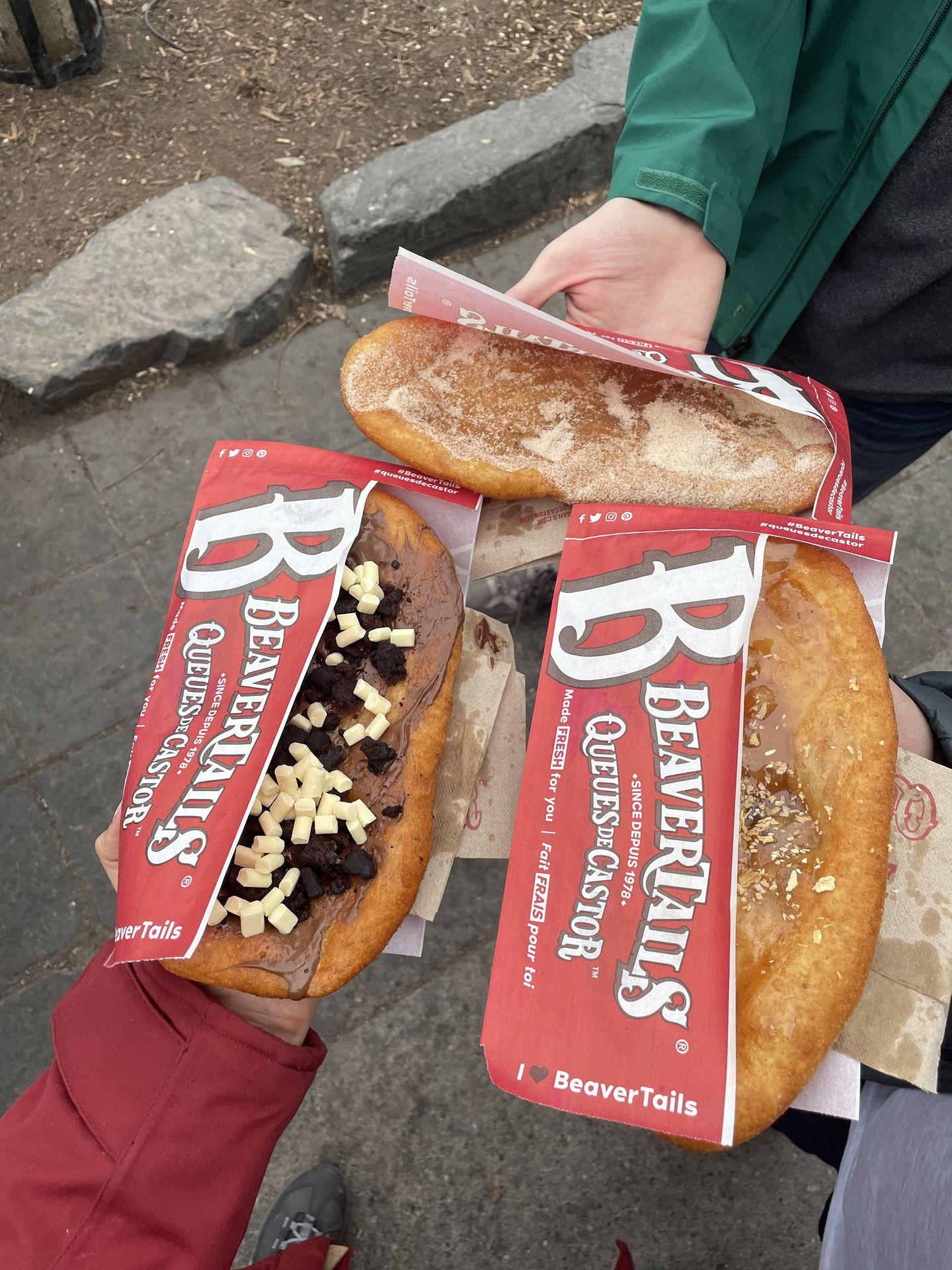 3 BeaverTails being held up, one has nutella and the others have cinnamon sugar.