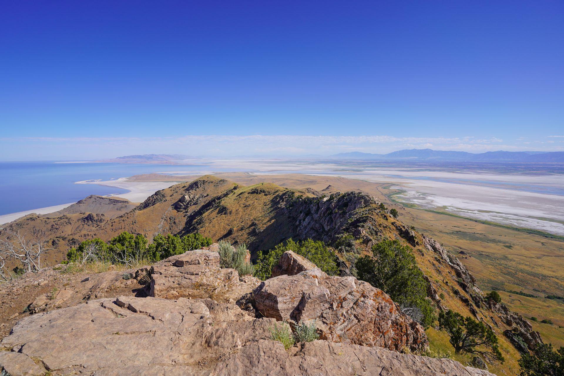 A view of Angelope Island from up high on a trail. There are areas of white sand and the Great Salt Lake surrounding the island.