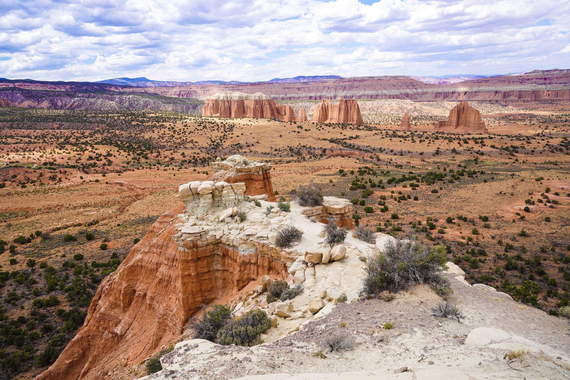 An expansive valley with various orange, rock formations with white caps. This iconic view is located in the Cathedral Valley area of Capitol Reef.