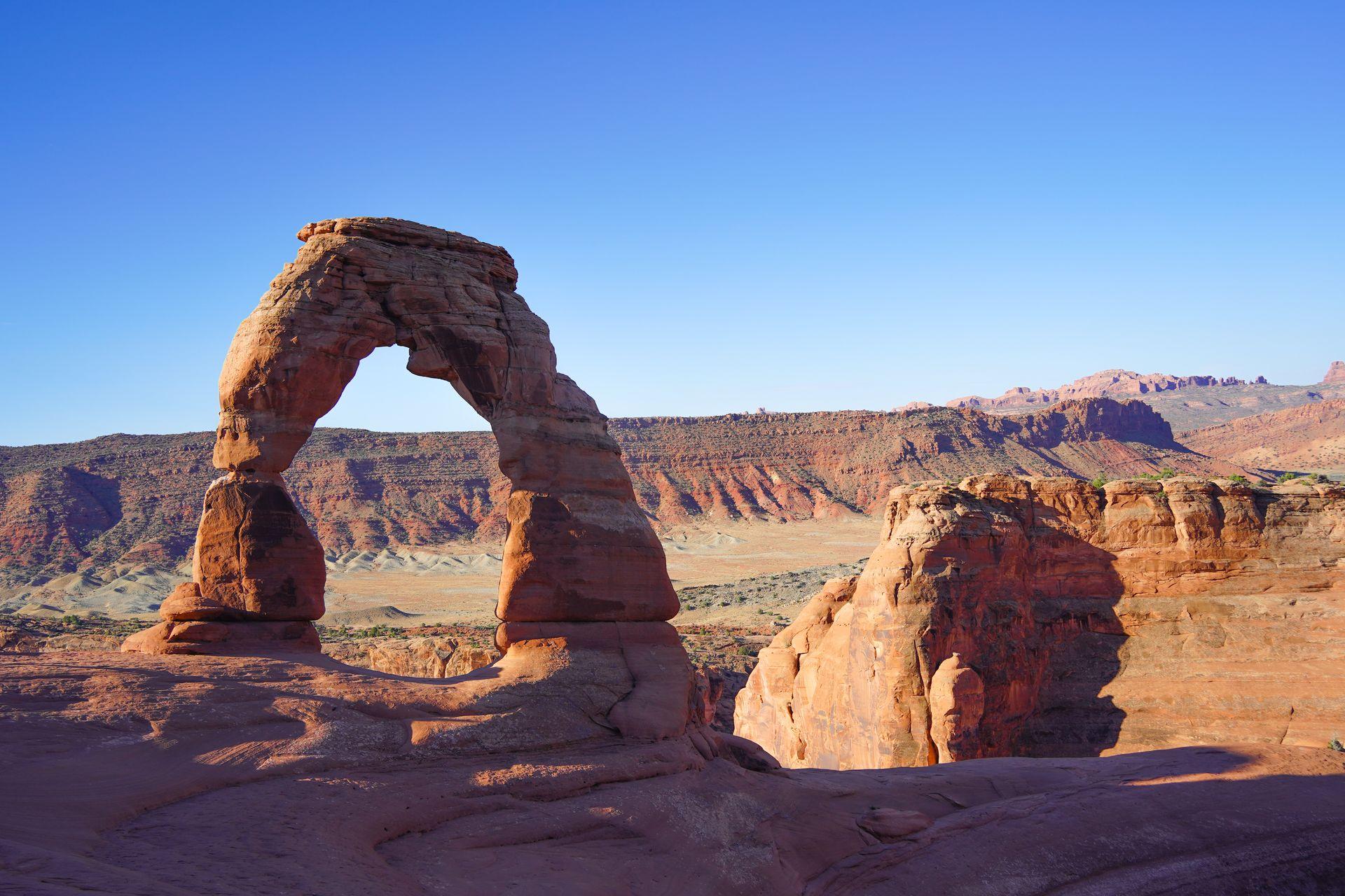The famous Delicate Arch in Arches National Park. The giant arch stands alone and is framed to the left.