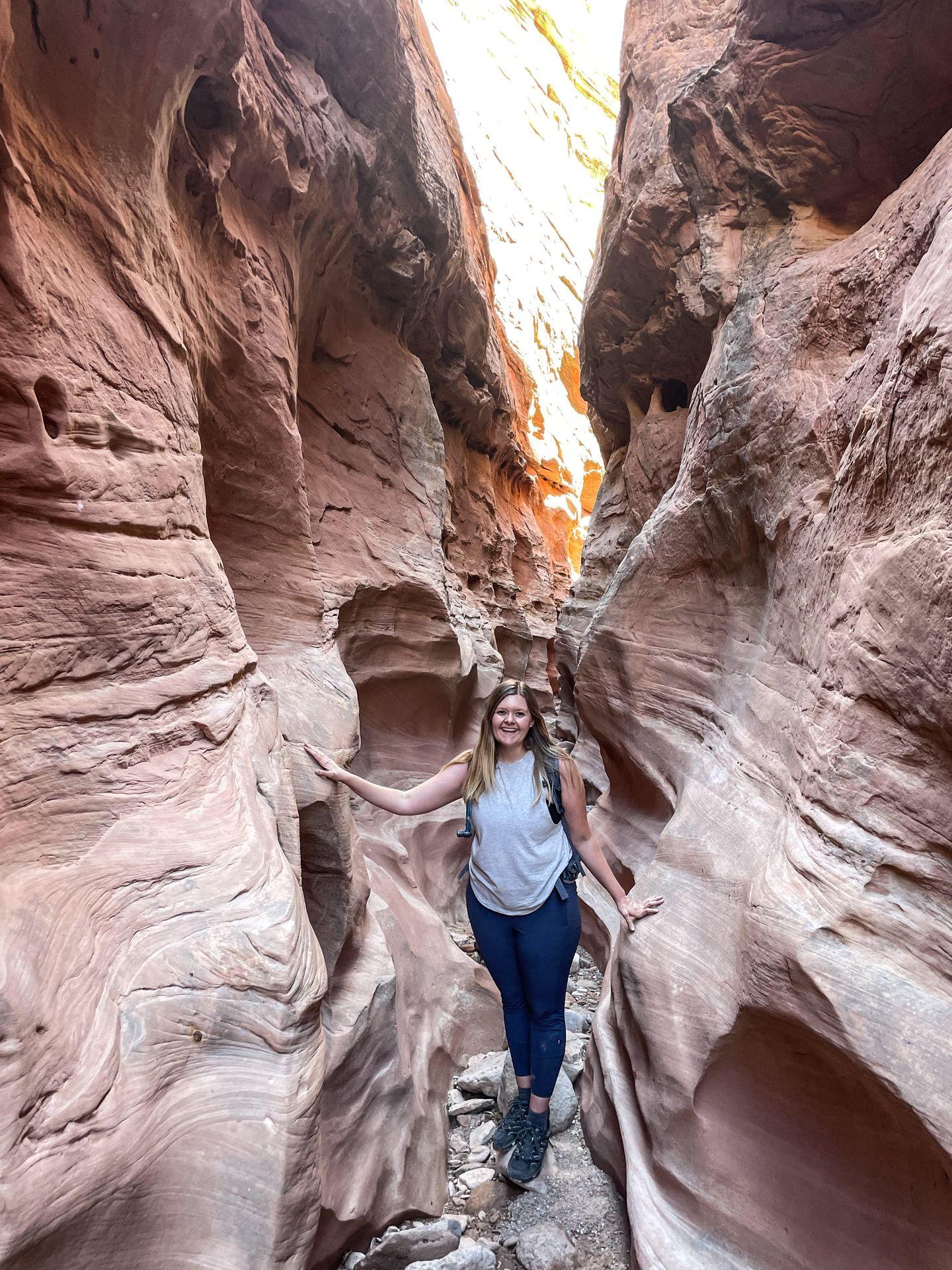 Lydia standing inside a narrow, orange slot canyon in Goblin Valley State Park.