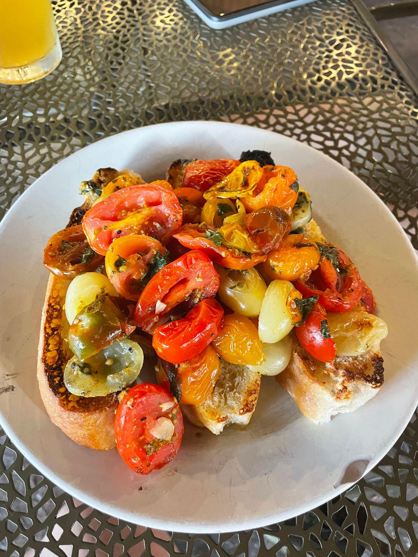 Three toasted pieces of bread topped with colorful cherry tomatoes at Antica Forma.