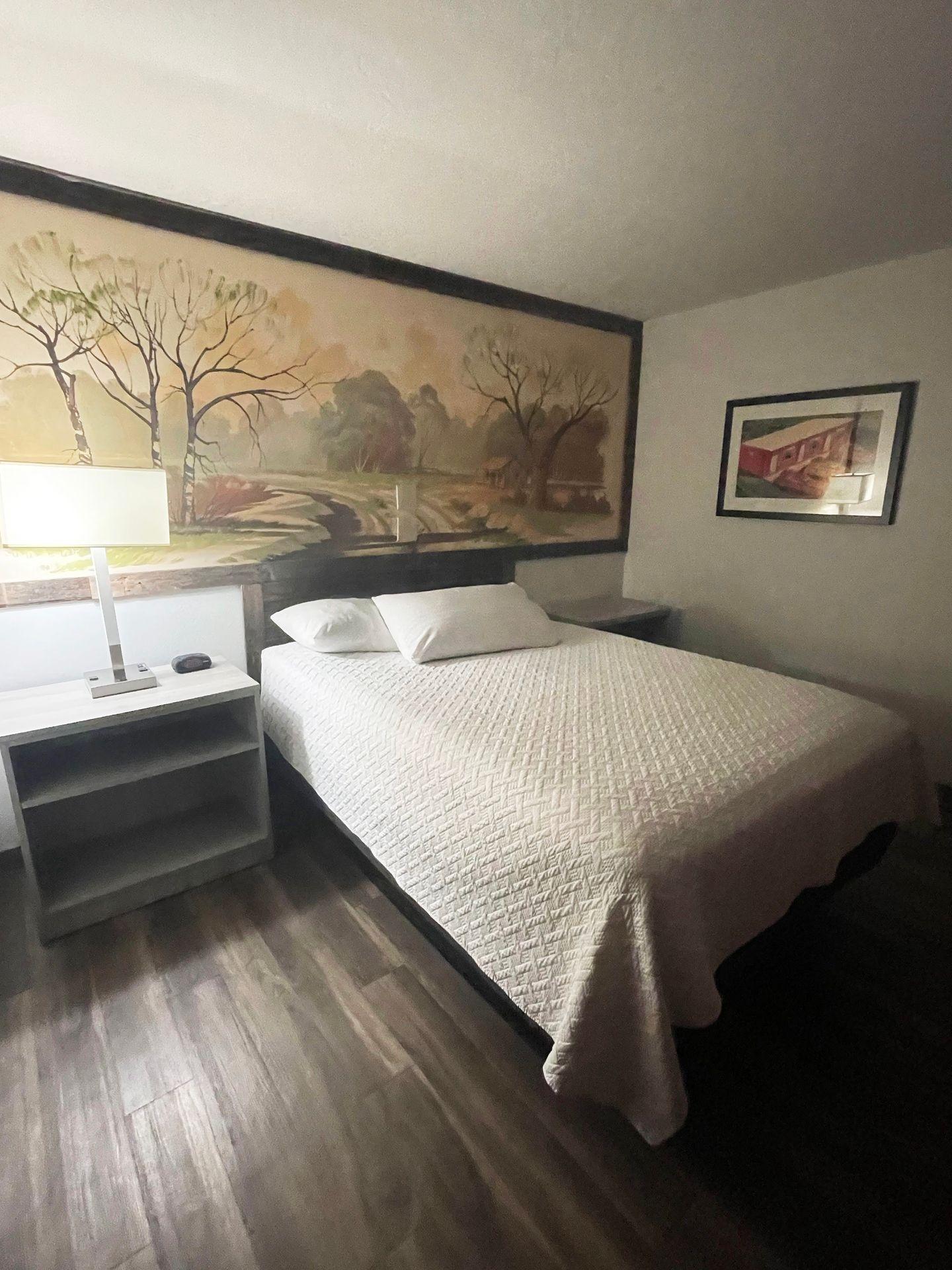 The inside of a standard room at Expedition Lodge. There is a bed with a large piece of artwork behind it.