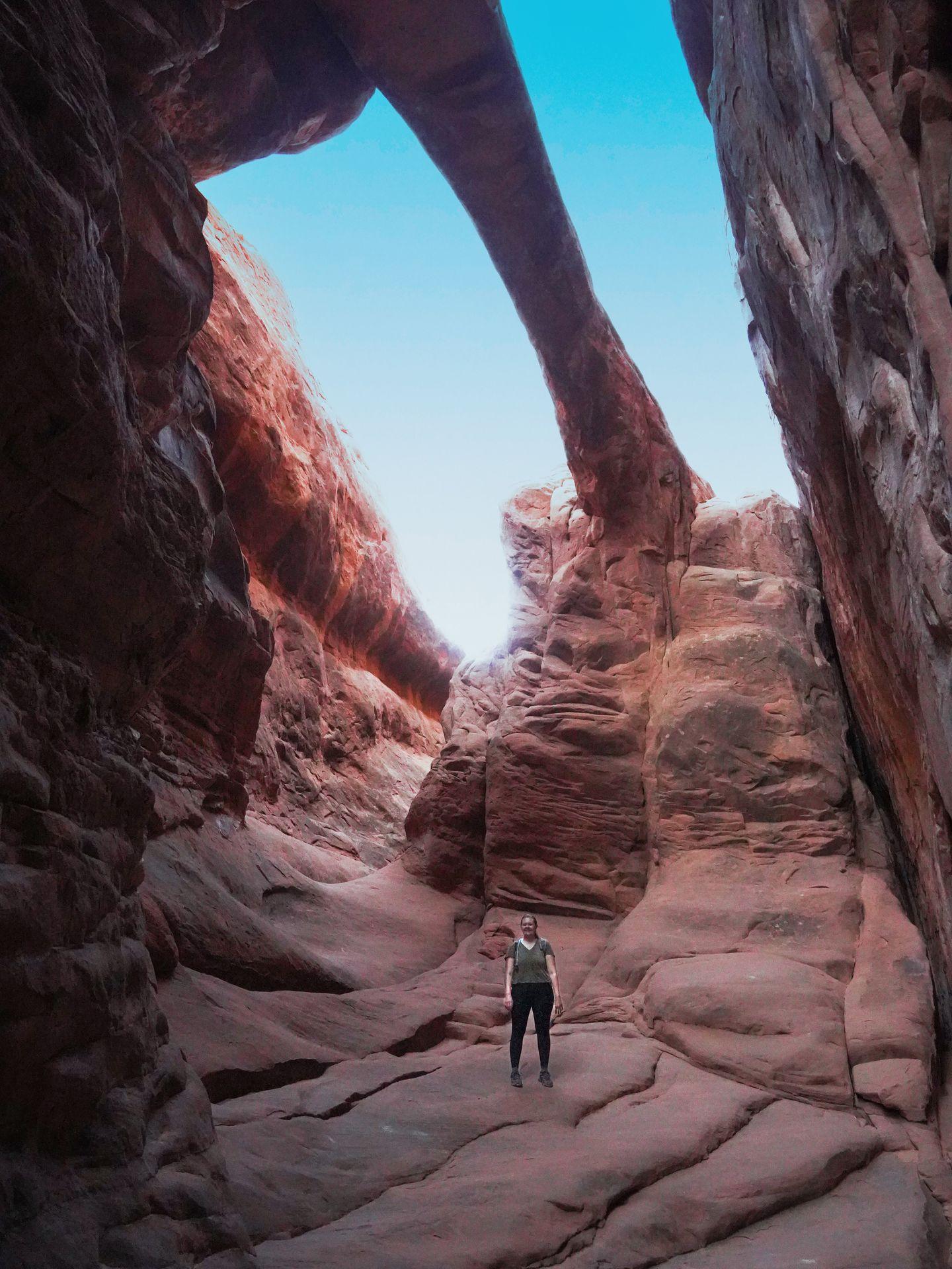 Lydia standing underneath the Surprise Arch on the Fiery Furnace trail
